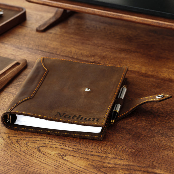 Classic brown leather binder on wooden desk with pen holder and name engraving