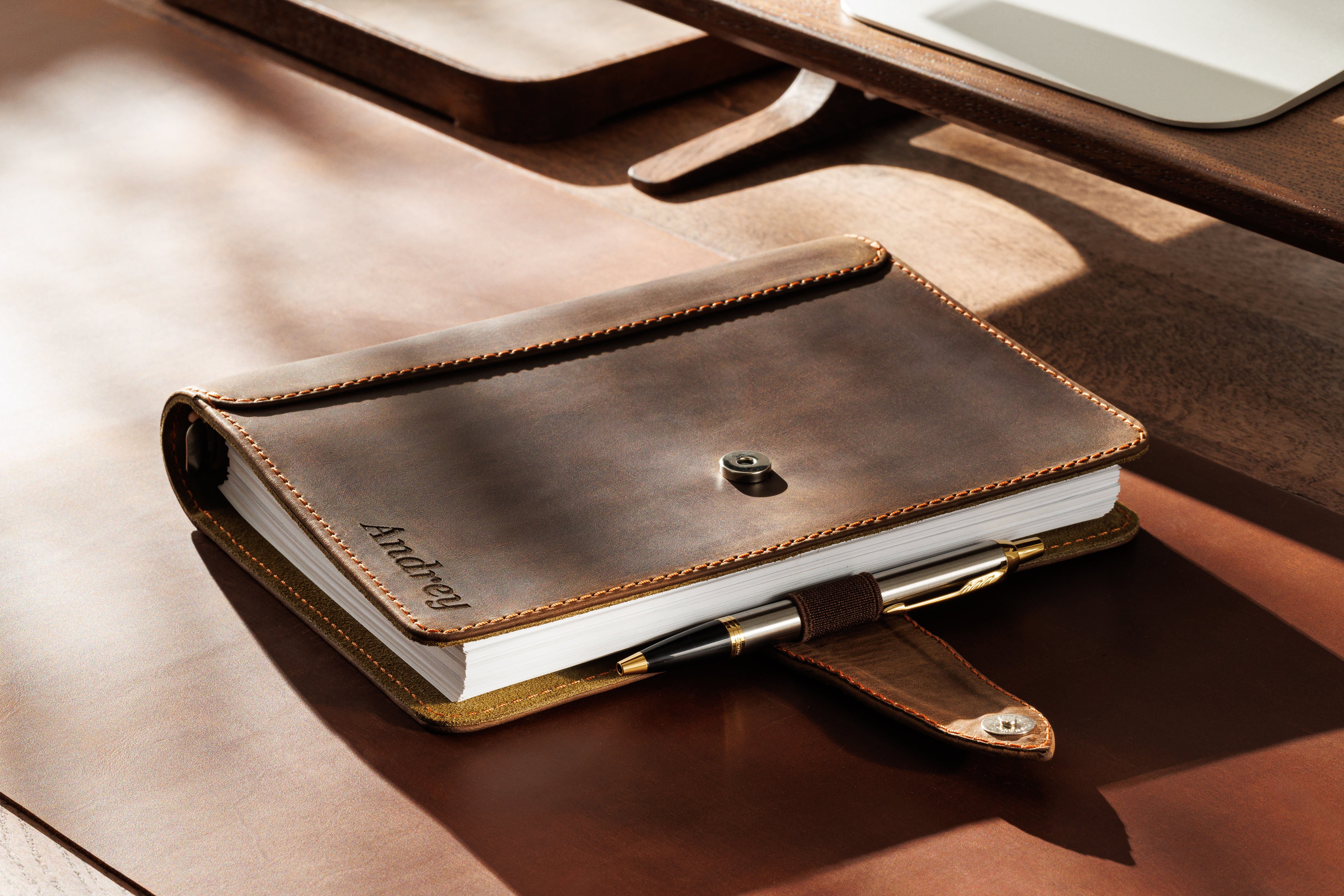 Handmade leather organizer open on a desk showing credit card slots and metal rings
