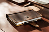 Handmade leather organizer open on a desk showing credit card slots and metal rings