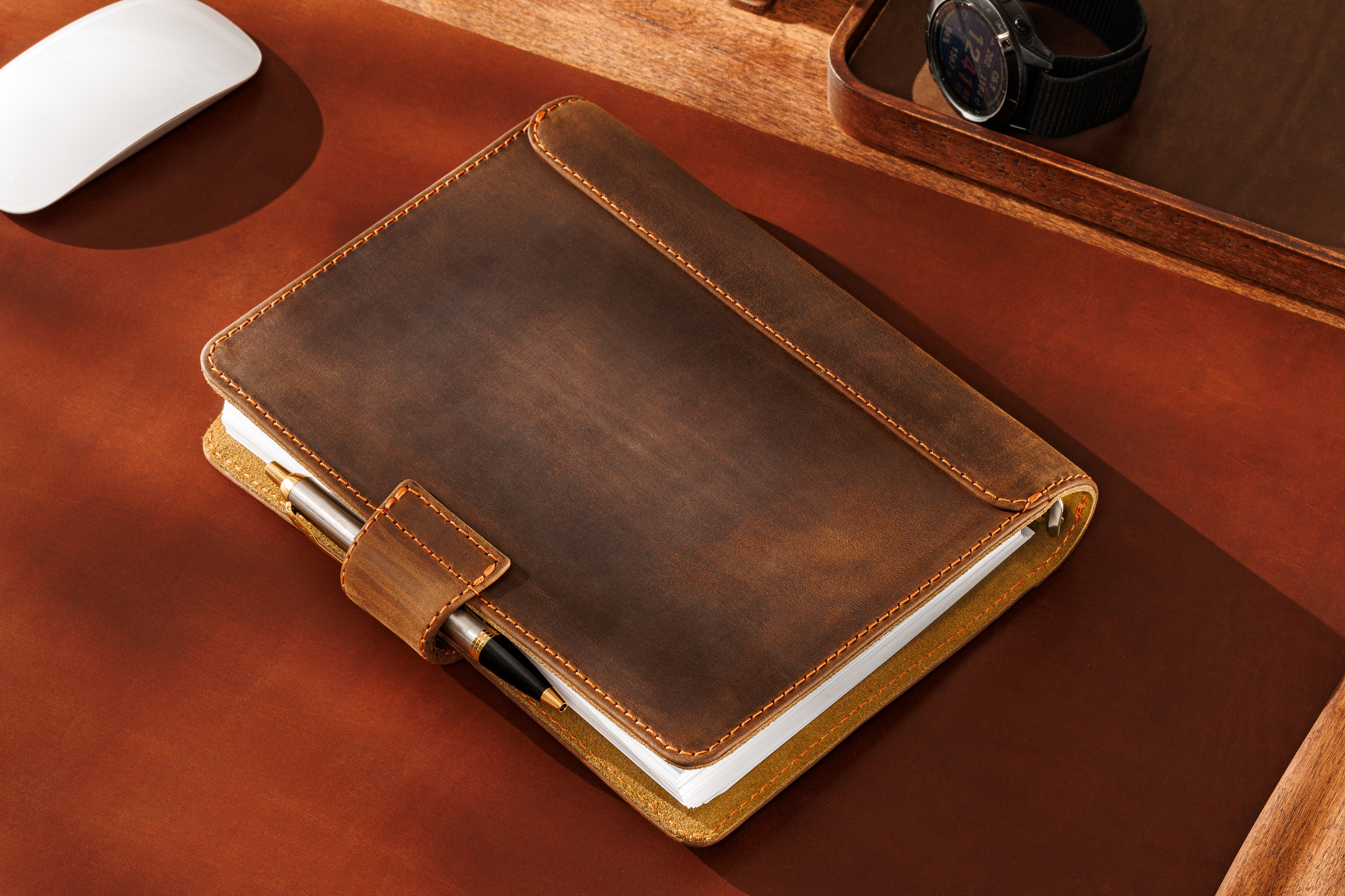 Light brown leather journal with contrast stitching and refillable pages on warm-toned background