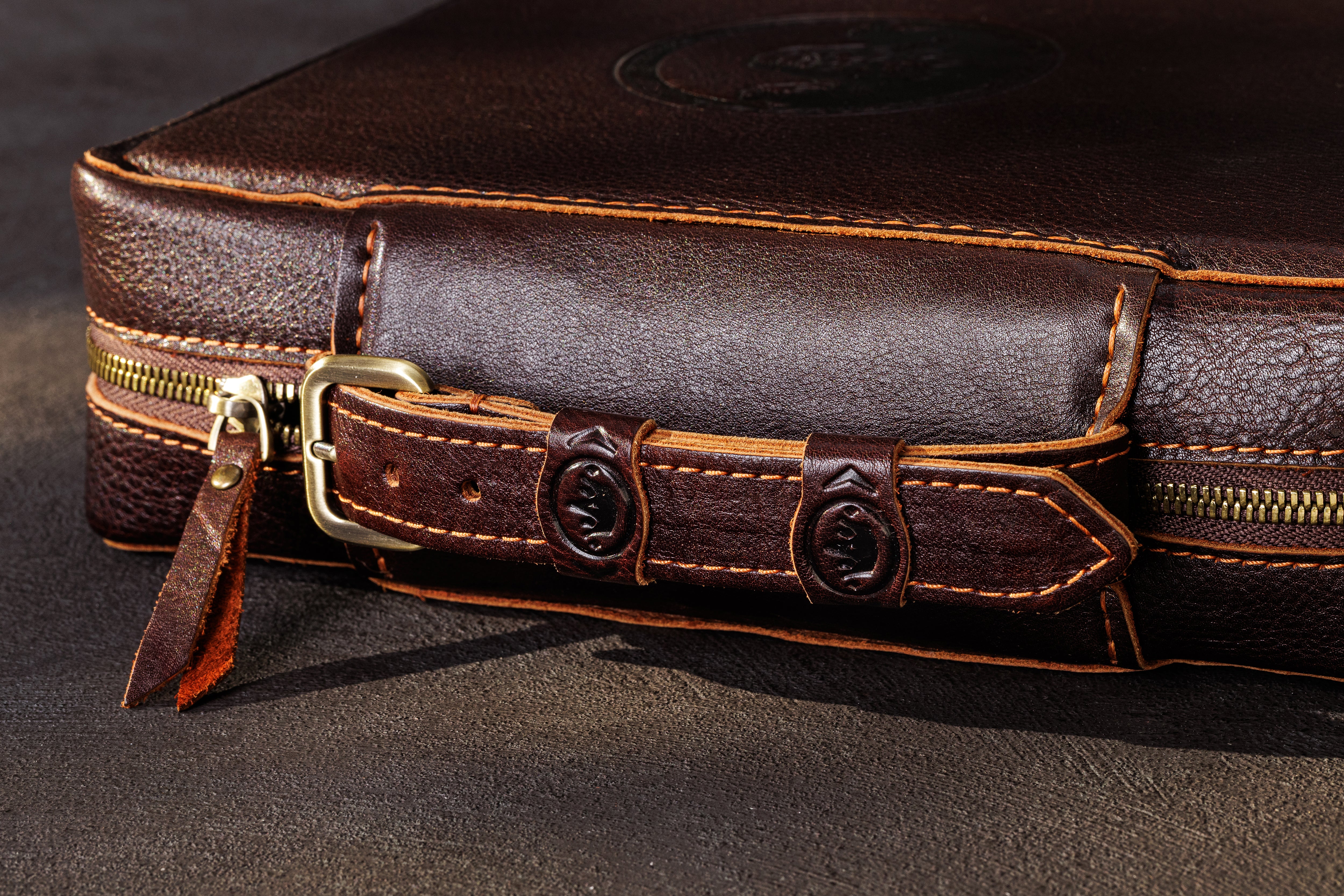 Close-up of dark brown leather money organizer carrying handle, antique zipper and contrast stitching