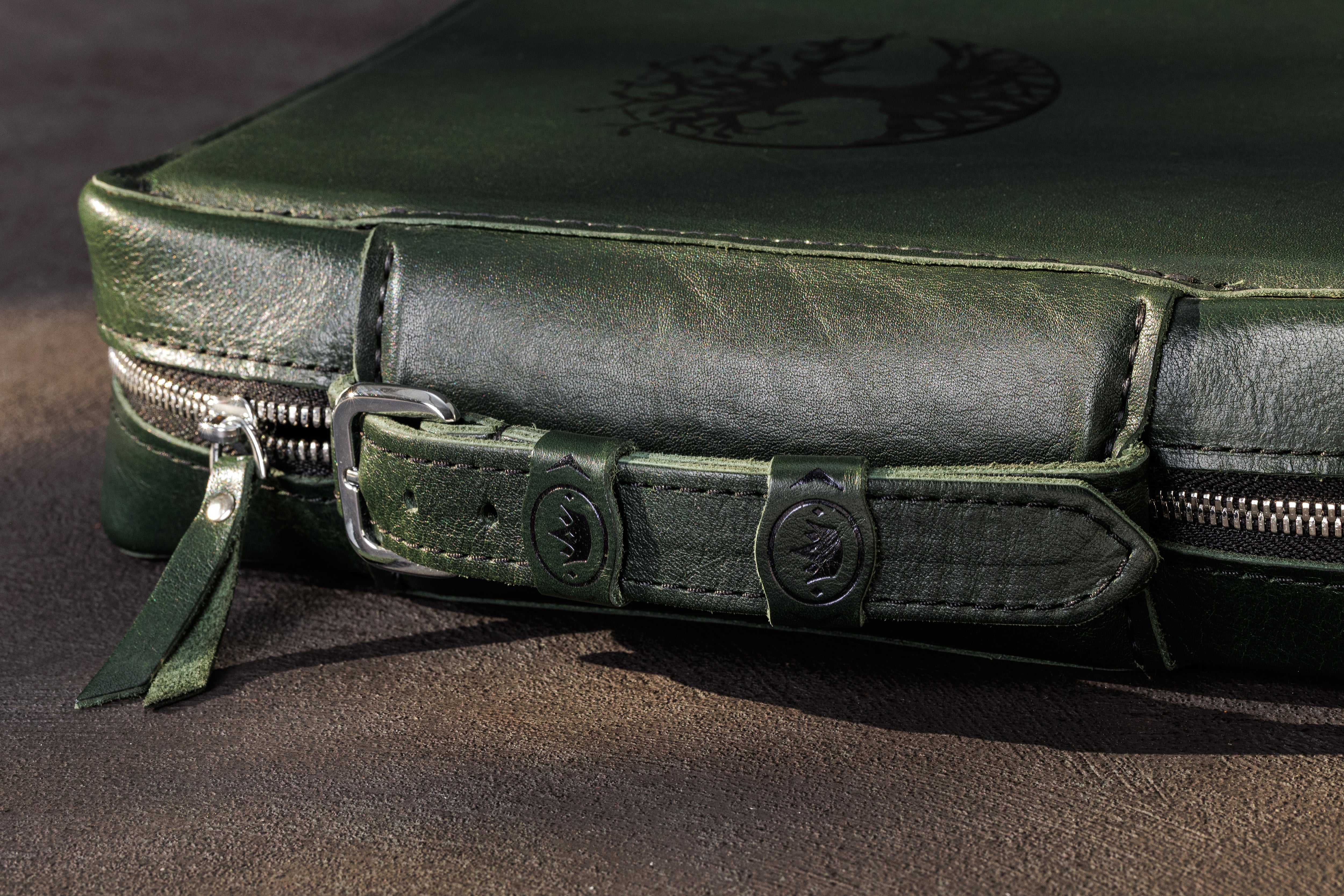 Close-up of dark green leather cash organizer handle, zipper closure and stitched carrying strap