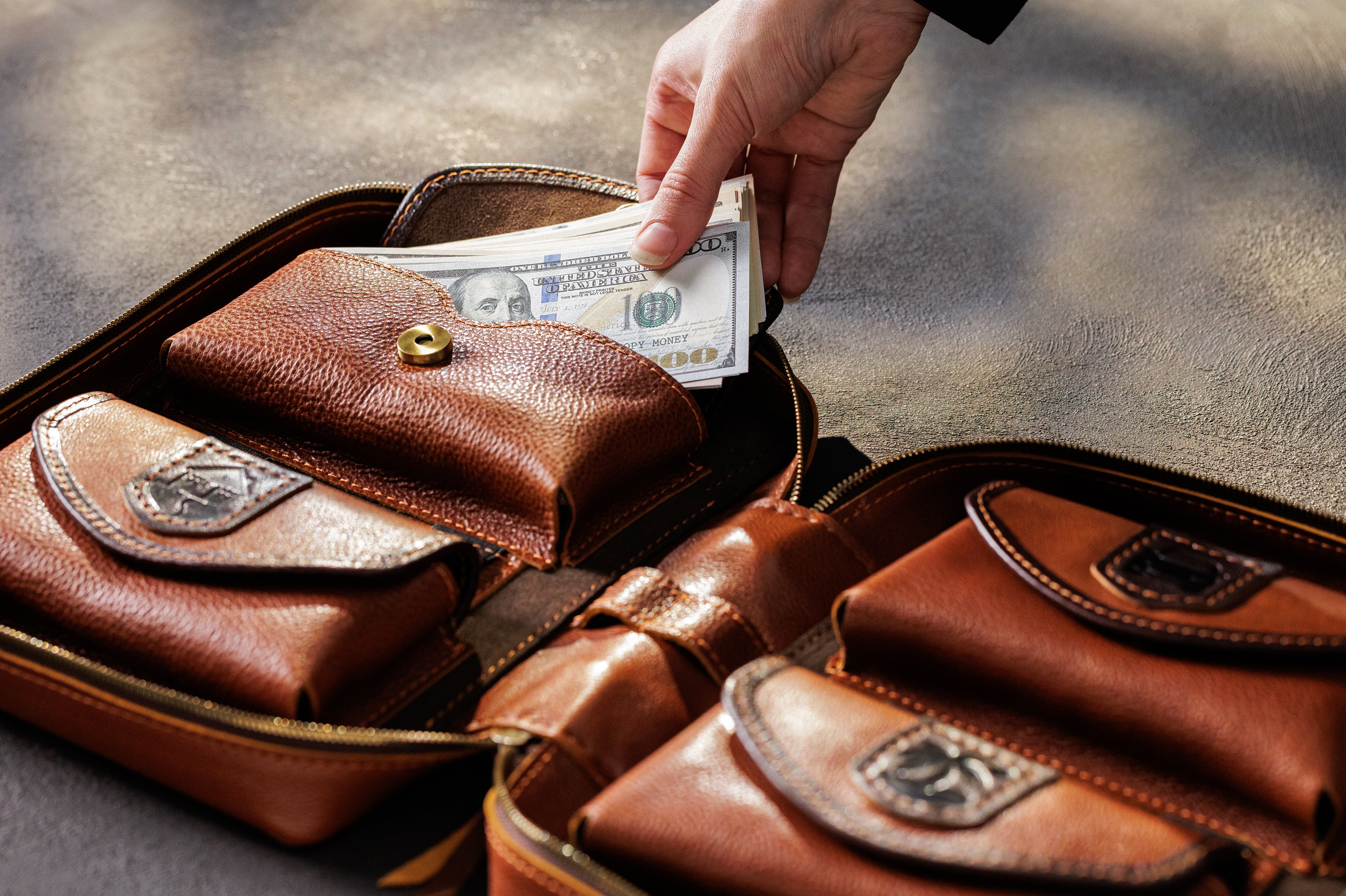 Hand removing cash from expandable camel leather bill pocket inside personalized money organizer