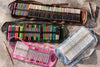 Collection of art supplies including colored pencils, markers, and pastels in various cases on a textured surface.