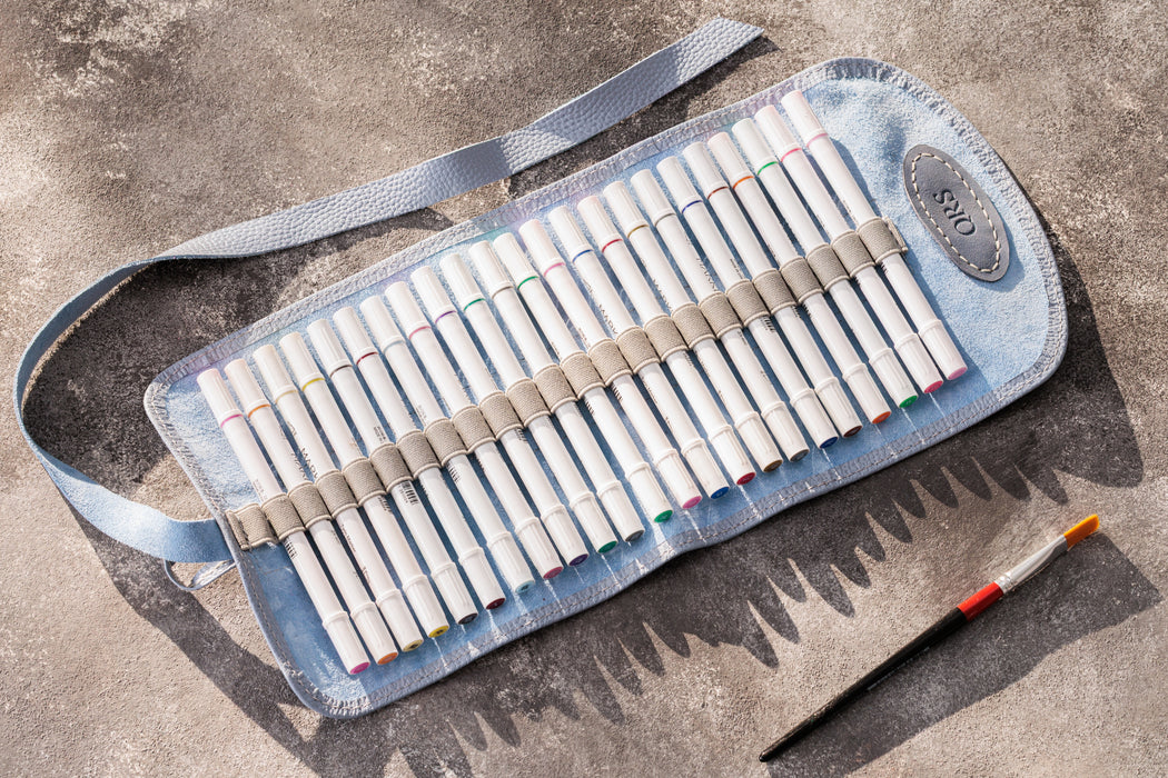 Set of colored pencils in a blue roll-up case on a concrete surface