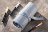 Roll of gray tape with paintbrushes on a concrete surface