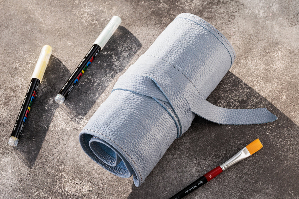 Roll of gray tape with paintbrushes on a concrete surface