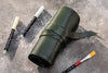 Green leather pencil case with markers and paintbrushes on a gray surface