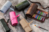 Rolls of colorful fabric on a textured surface with a paintbrush.