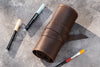 Brown leather roll with paintbrushes on a gray textured surface