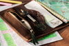 Leather sketchbook organizer with colored pencils and artist notebook.