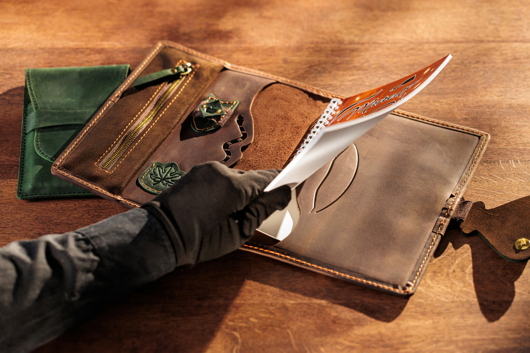 Handmade leather organizer open with spiral notebook.