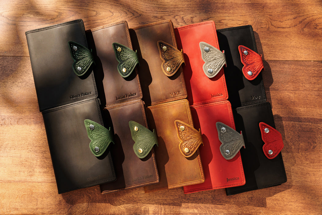 Set of leather wallets in various colors with decorative elements on a wooden surface