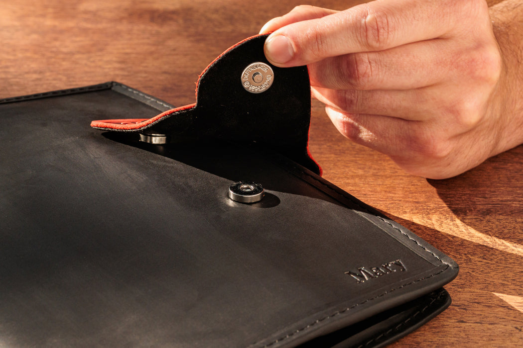 Empty black leather organizer with red butterfly clasp.