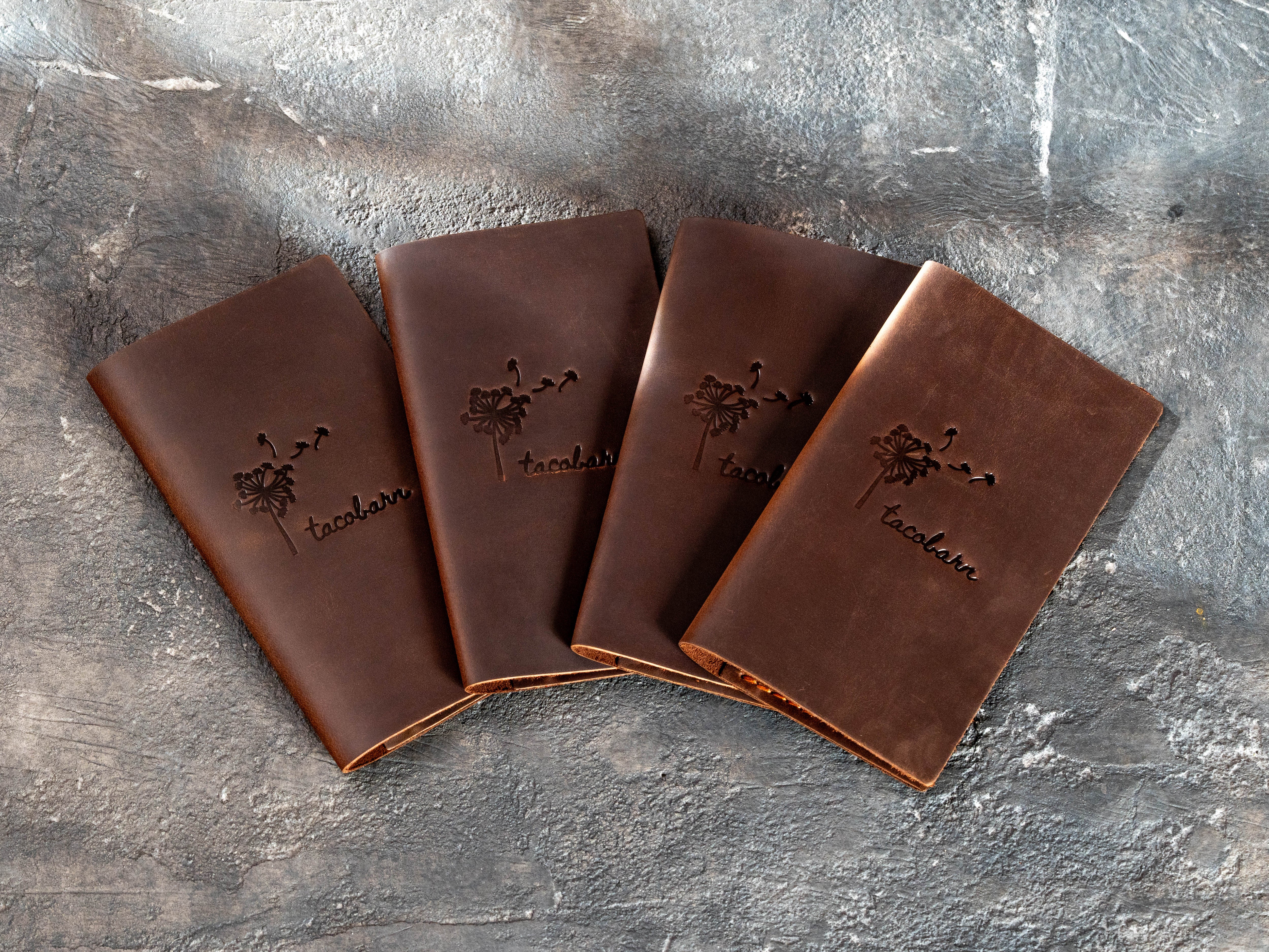 Four custom brown leather check presenters made for Taco Bar with matching dandelion logos