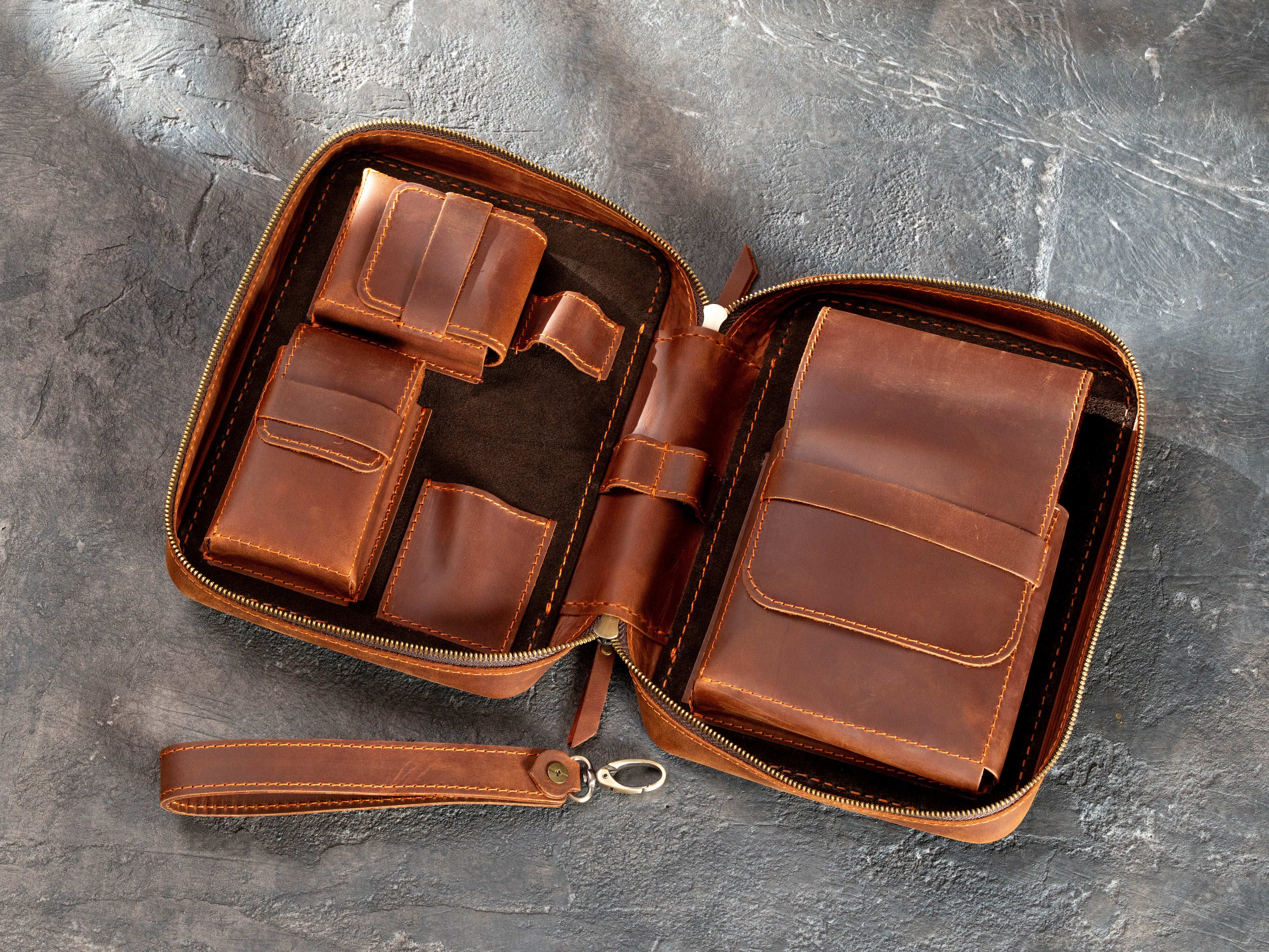 Open leather travel cigar organizer showing multiple stitched compartments and three cigars secured inside