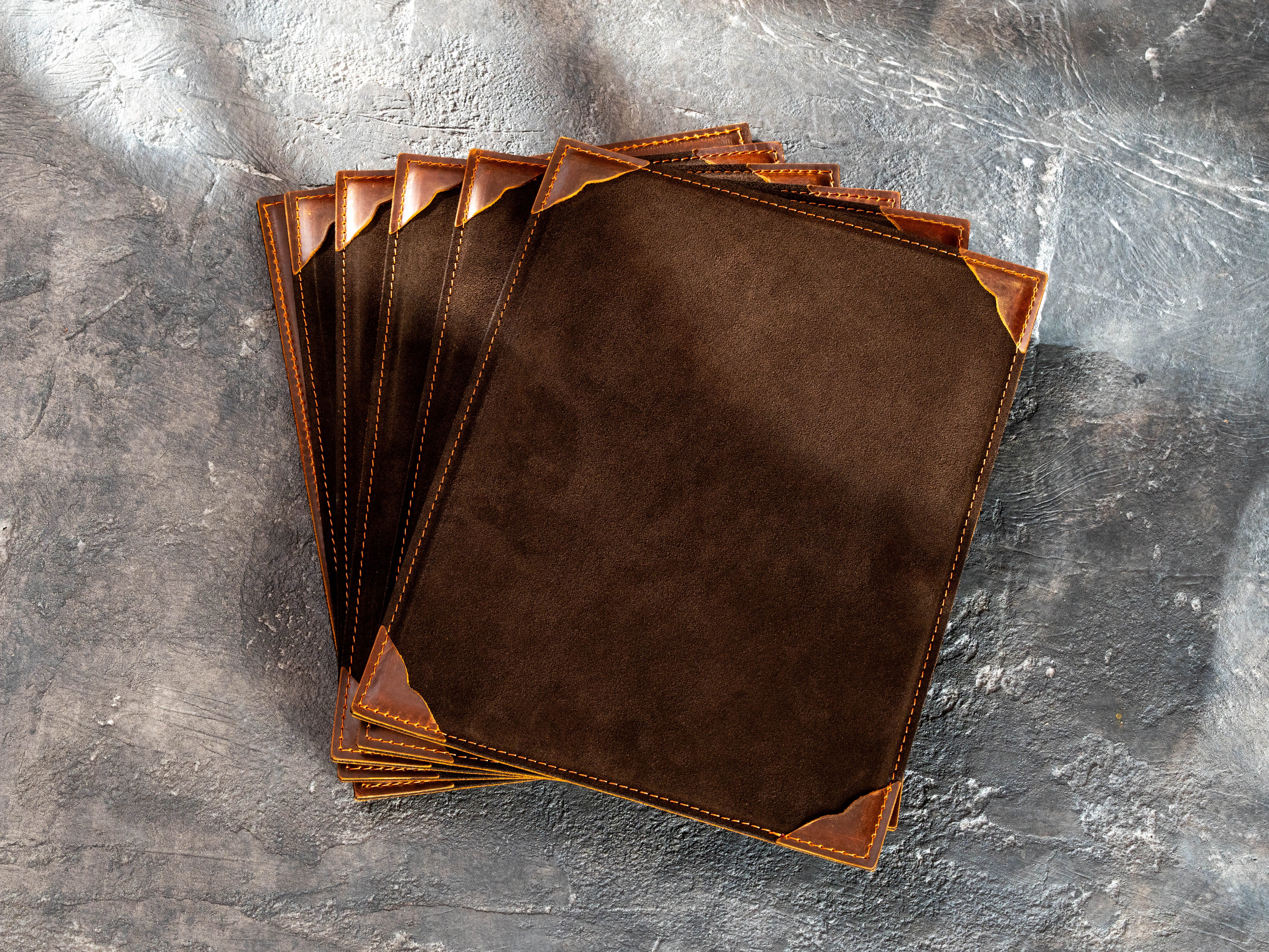 Stack of brown suede menu boards with stitched Chestnut leather corner holders for 8.5 × 11 inserts