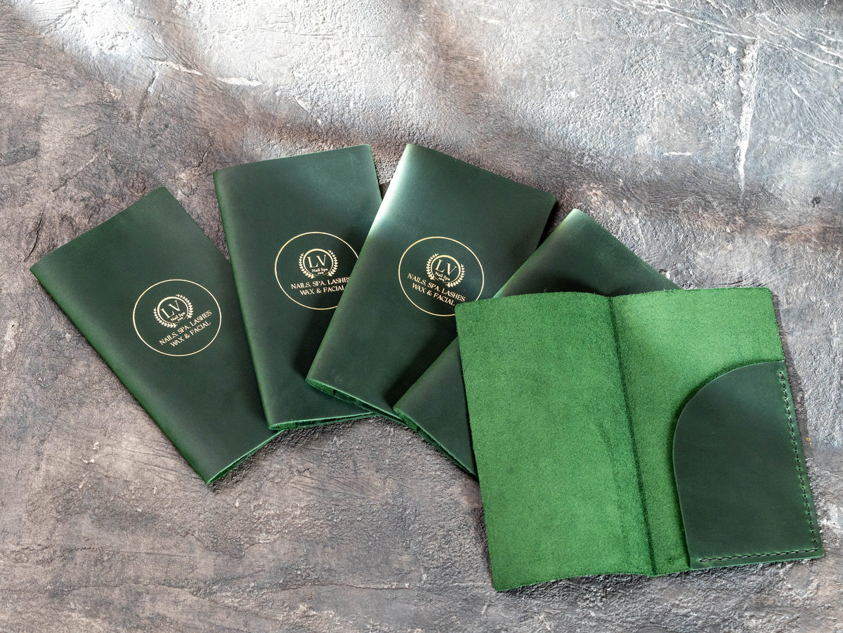 Green leather check presenters with gold personalization and open interior bill pocket