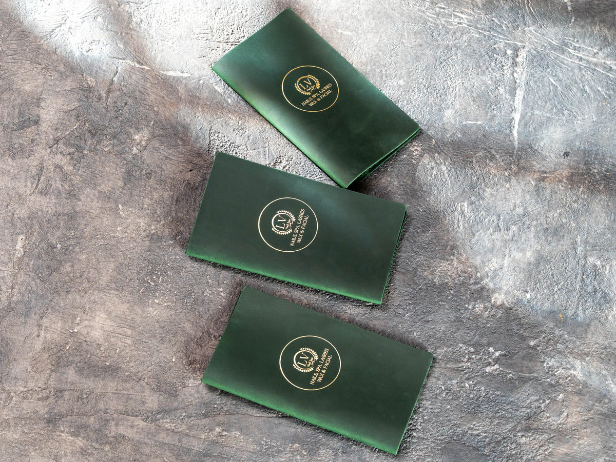 Custom green leather restaurant and spa check presenters with gold branding