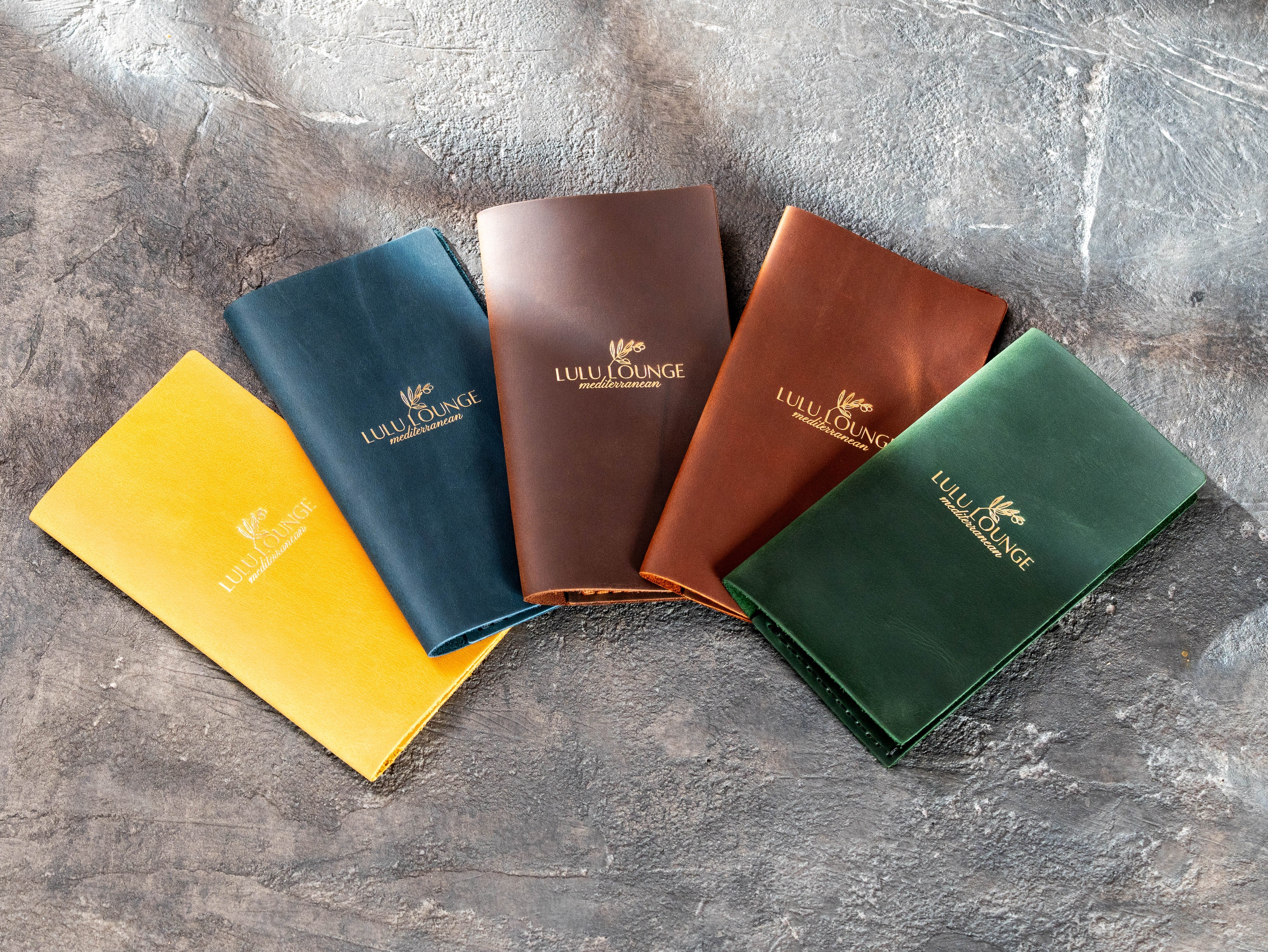 Custom leather check presenter samples in green, blue, yellow, brown and copper colors with business logo.
