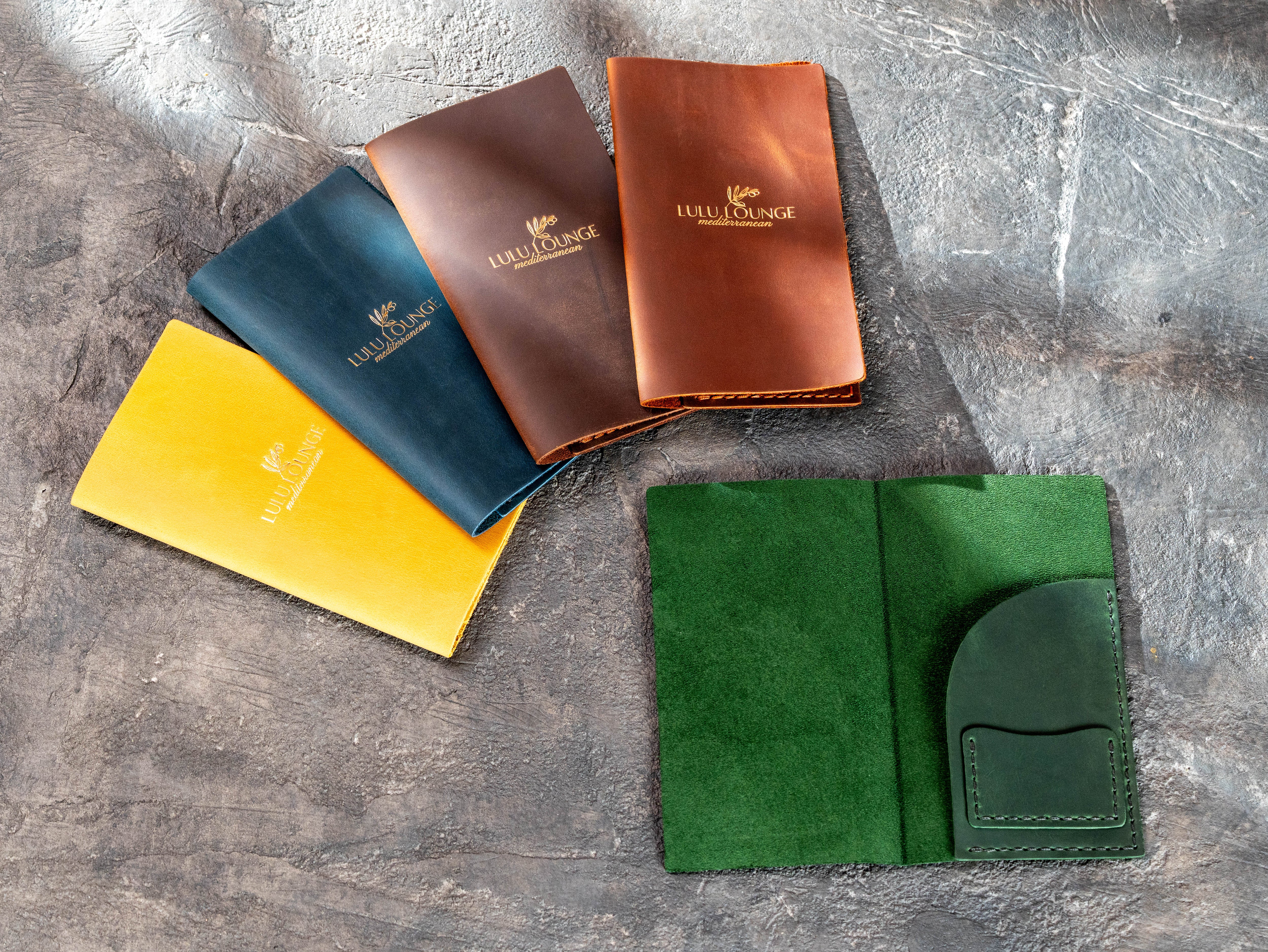 Leather check presenter sample set with custom logo and open green interior showing receipt and card pockets.