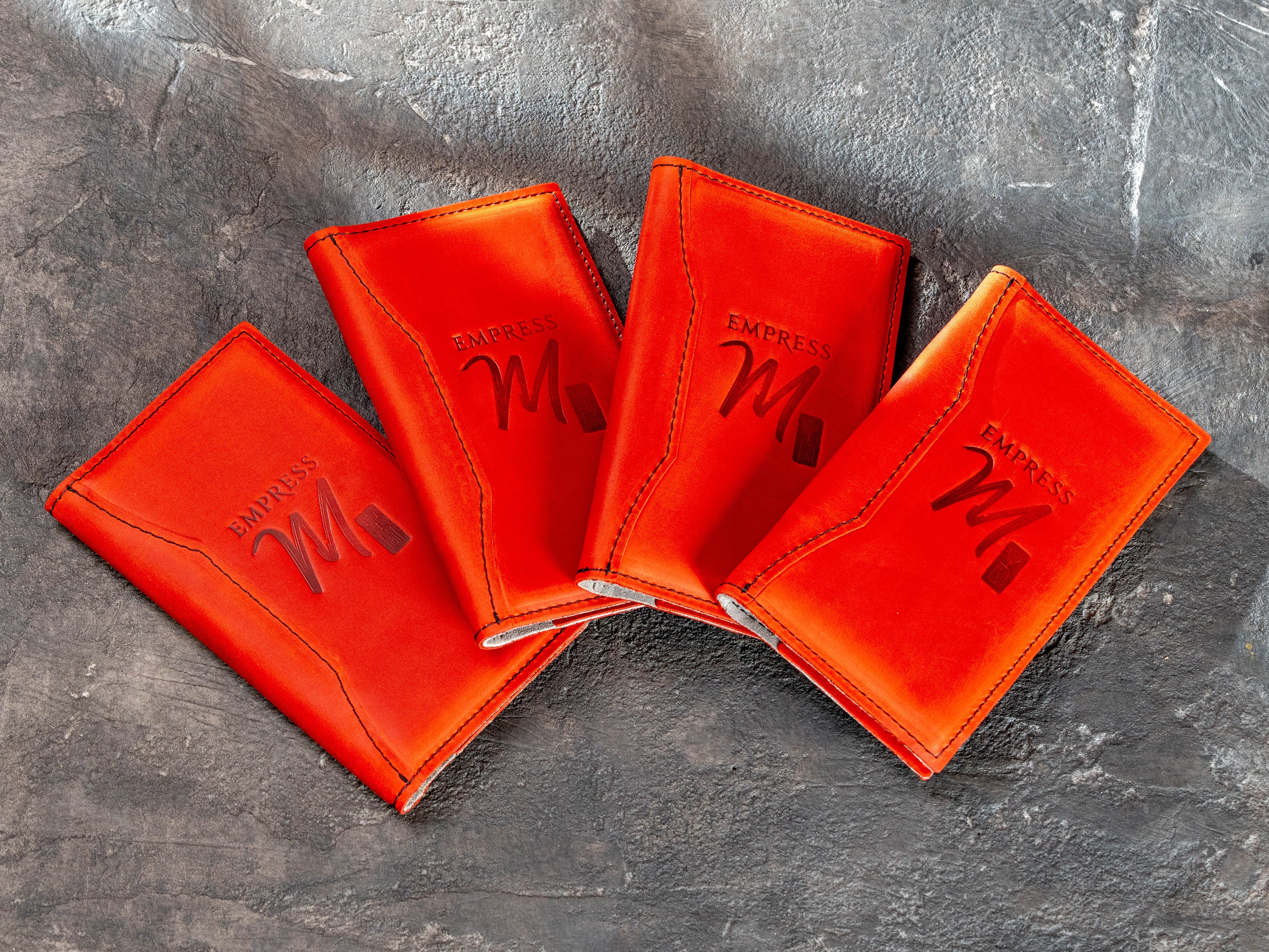 Custom red leather restaurant check presenters with embossed client logo and decorative stitched front design