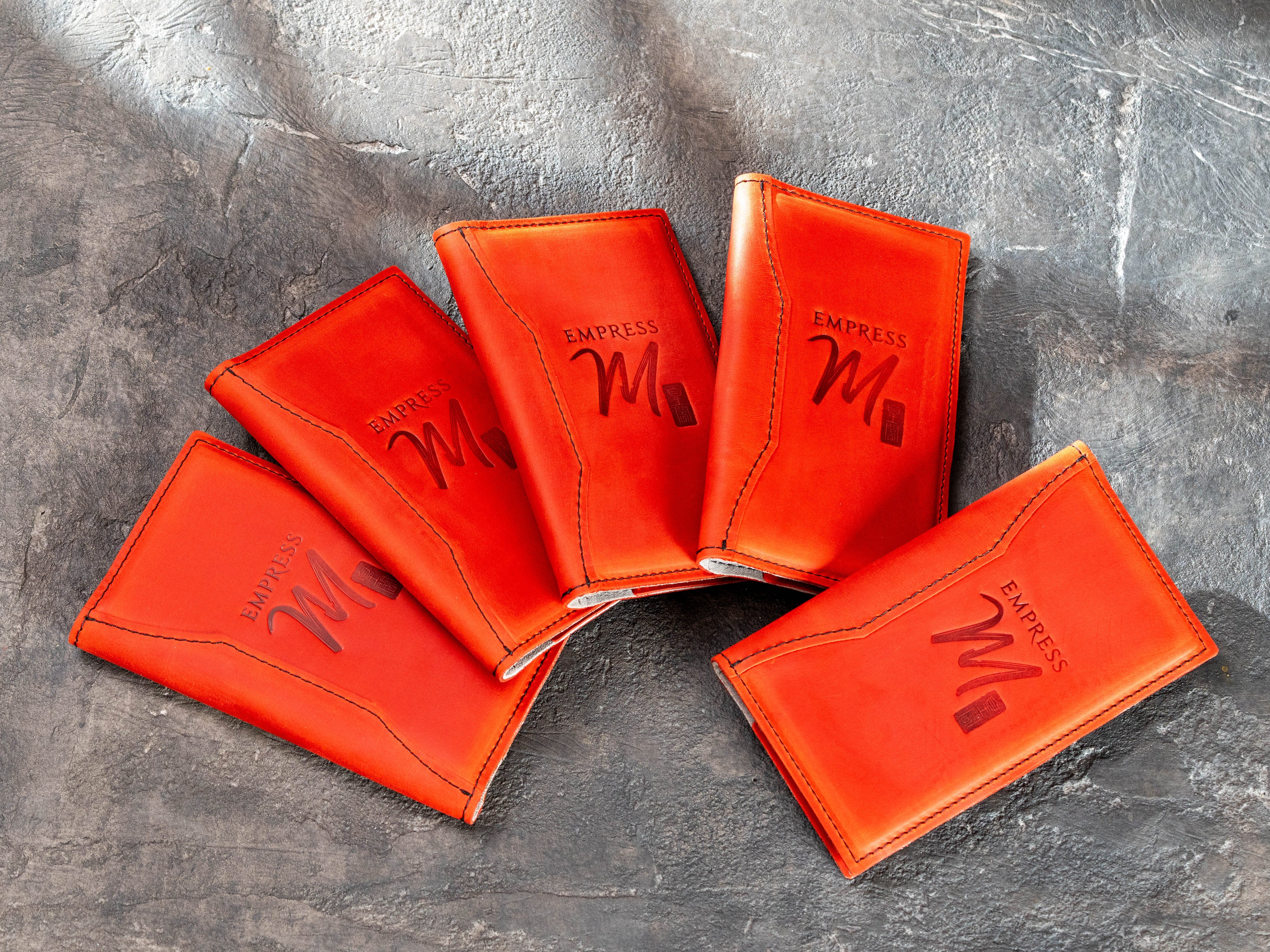 Group of red leather check presenters made as a custom restaurant order with logo personalization