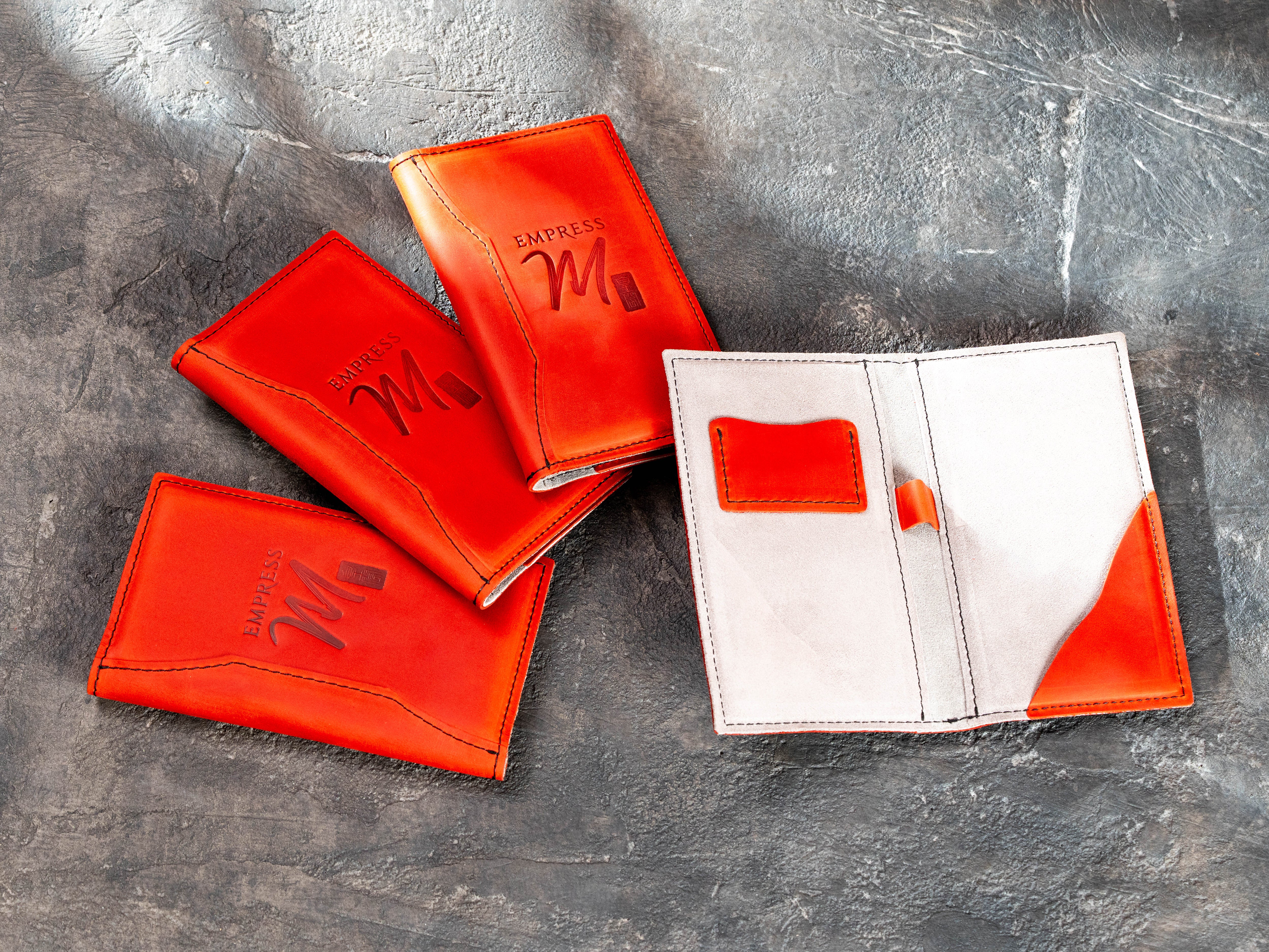 Open red leather check presenter showing card pocket, pen loop and curved receipt pocket