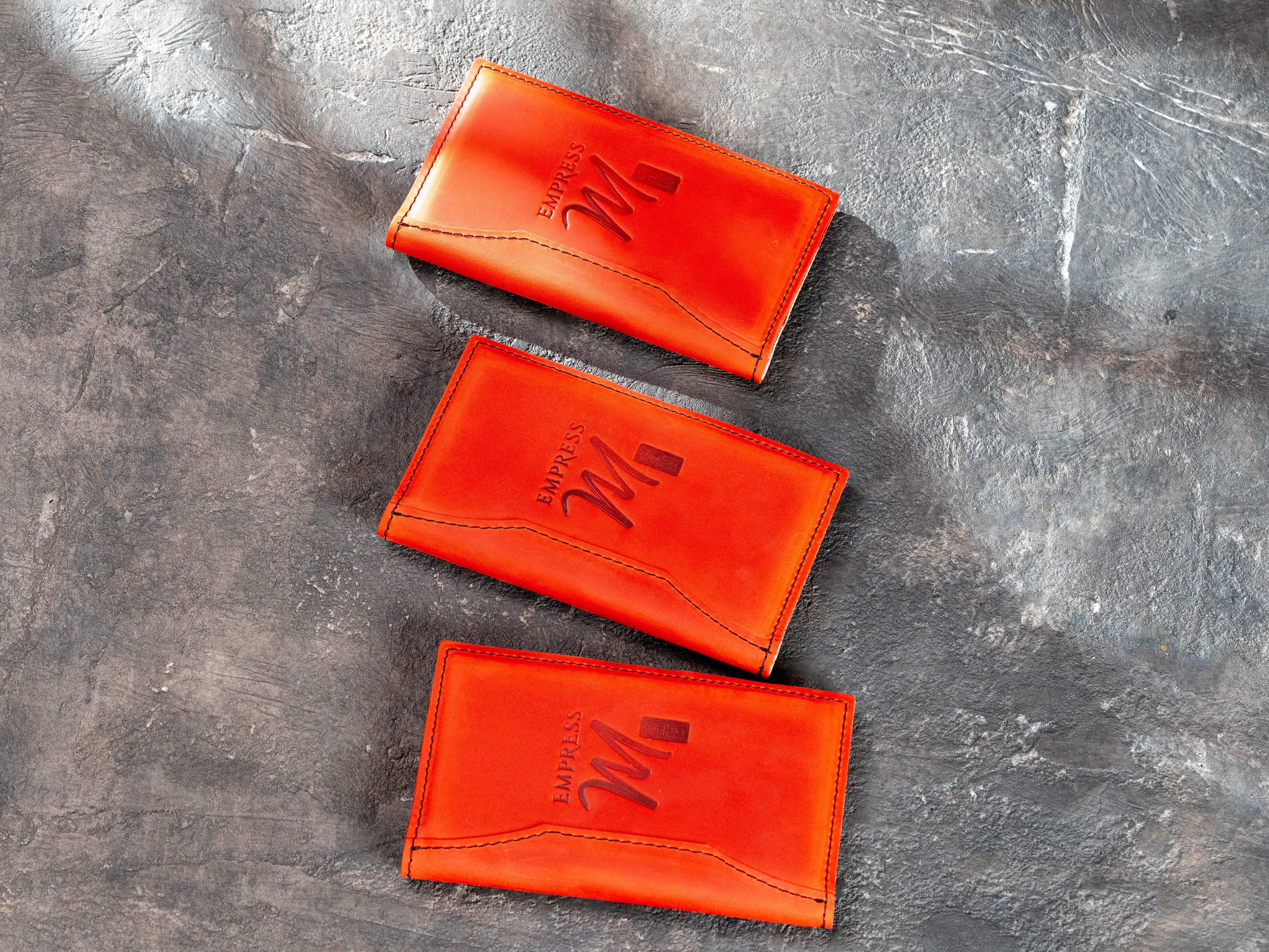 Three personalized red leather check presenters arranged on dark textured background