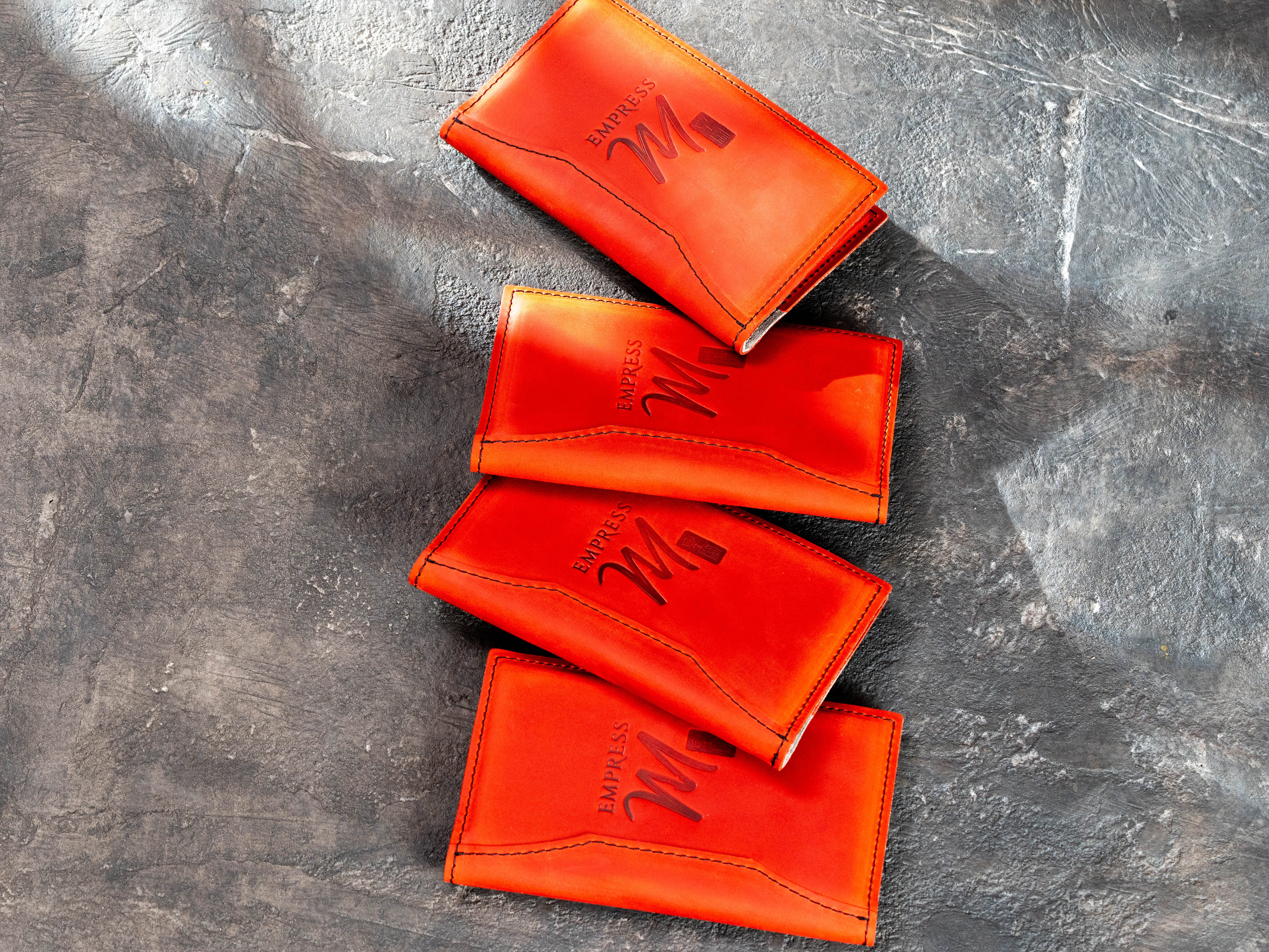 Four custom red leather bill holders made for a restaurant client