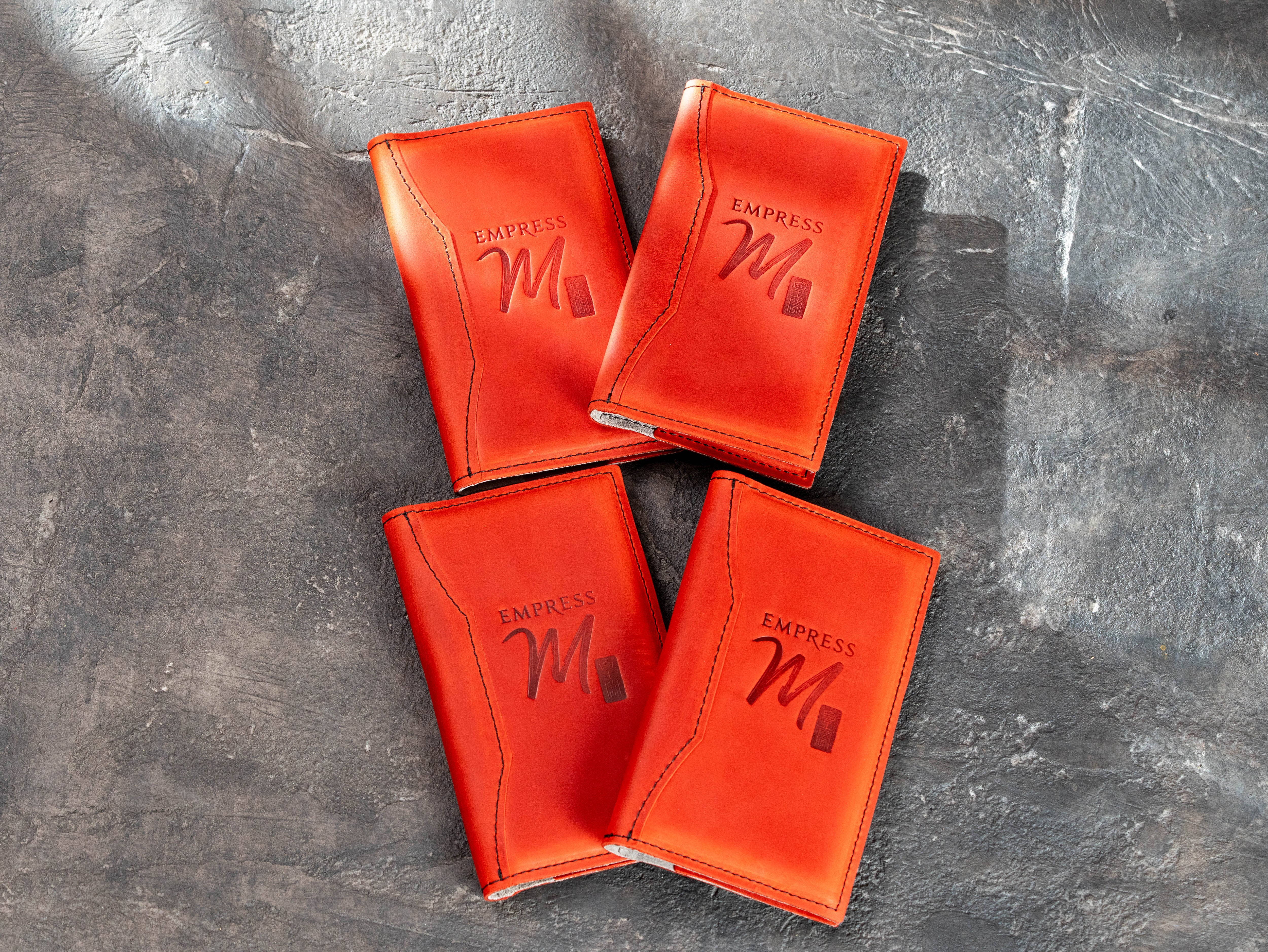 4 red leather restaurant check presenters with embossed logo and stitched edges