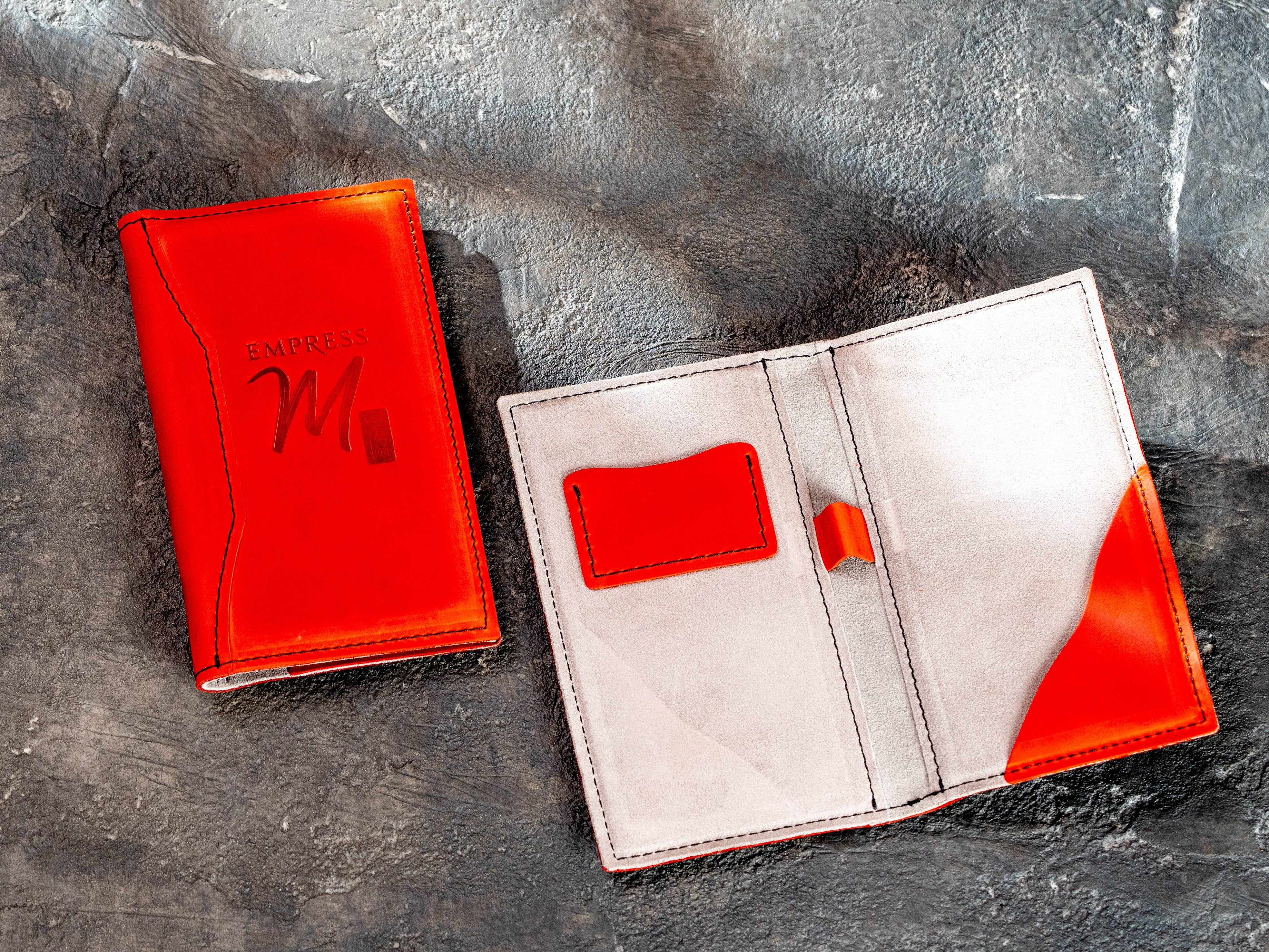 Red leather check presenter open to show interior card pocket, pen holder and bill pocket