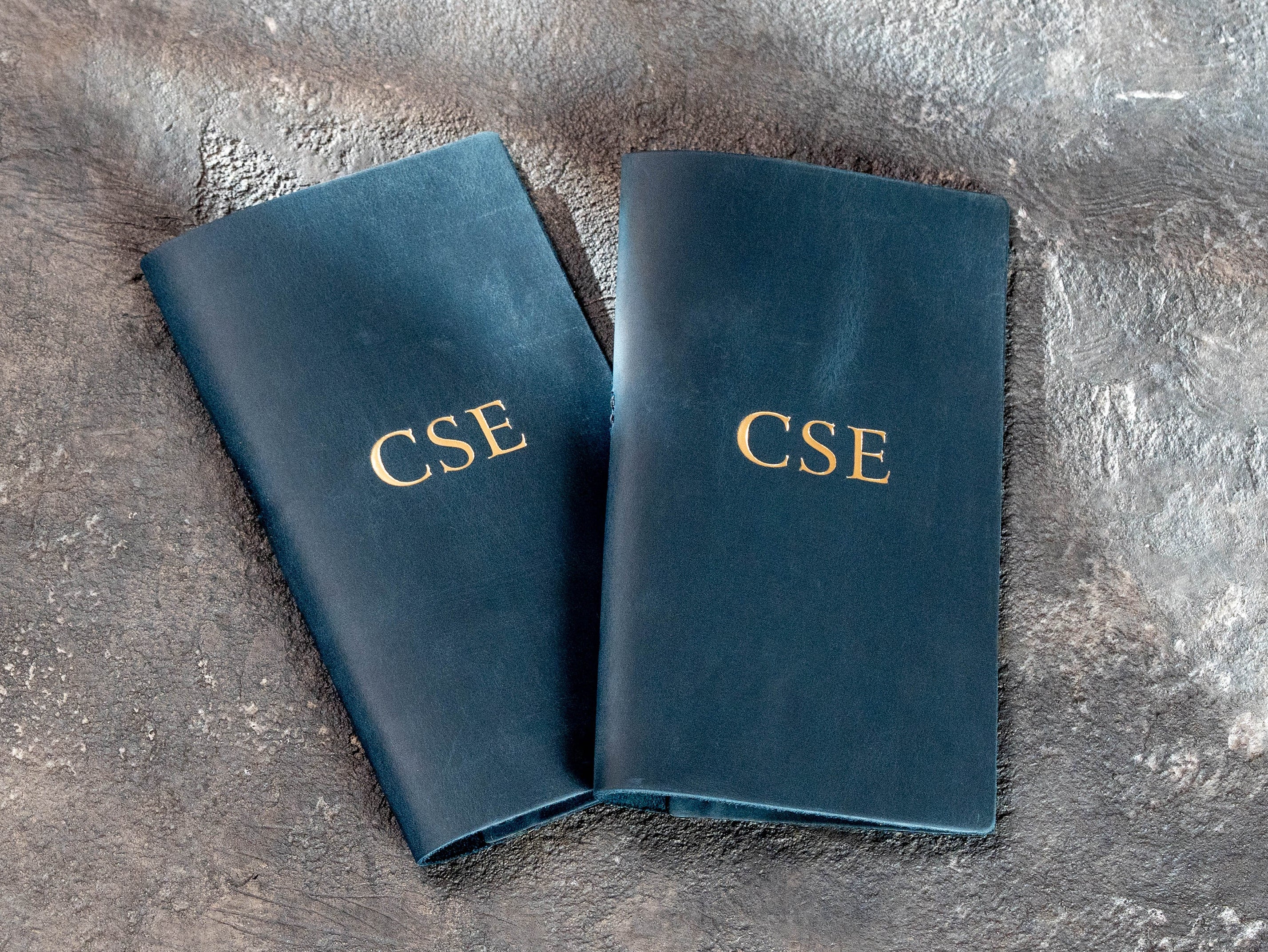 Blue restaurant bill holders with gold logo personalization and stitched leather construction