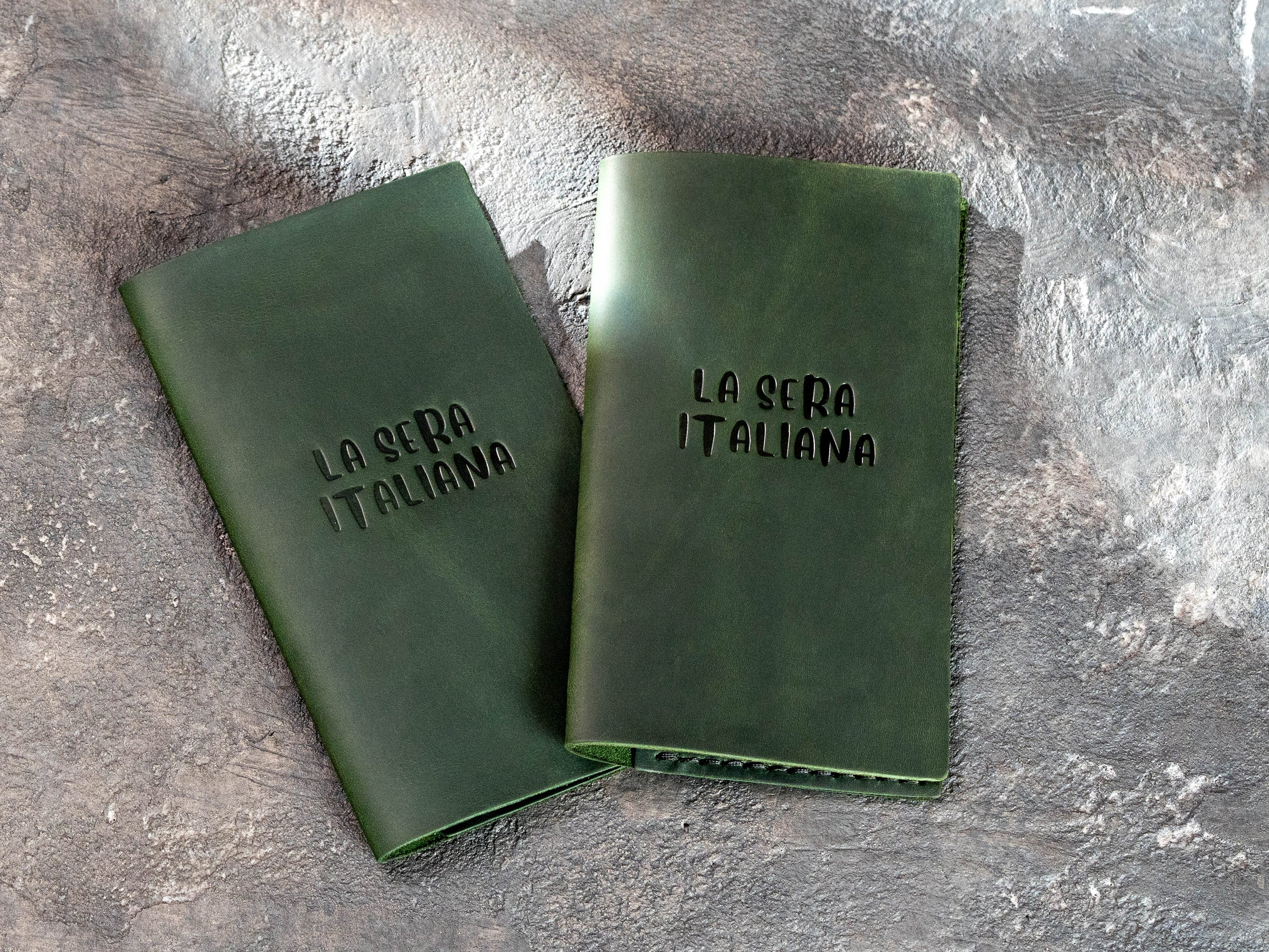 Two dark green leather restaurant bill holders with custom blind embossed logo