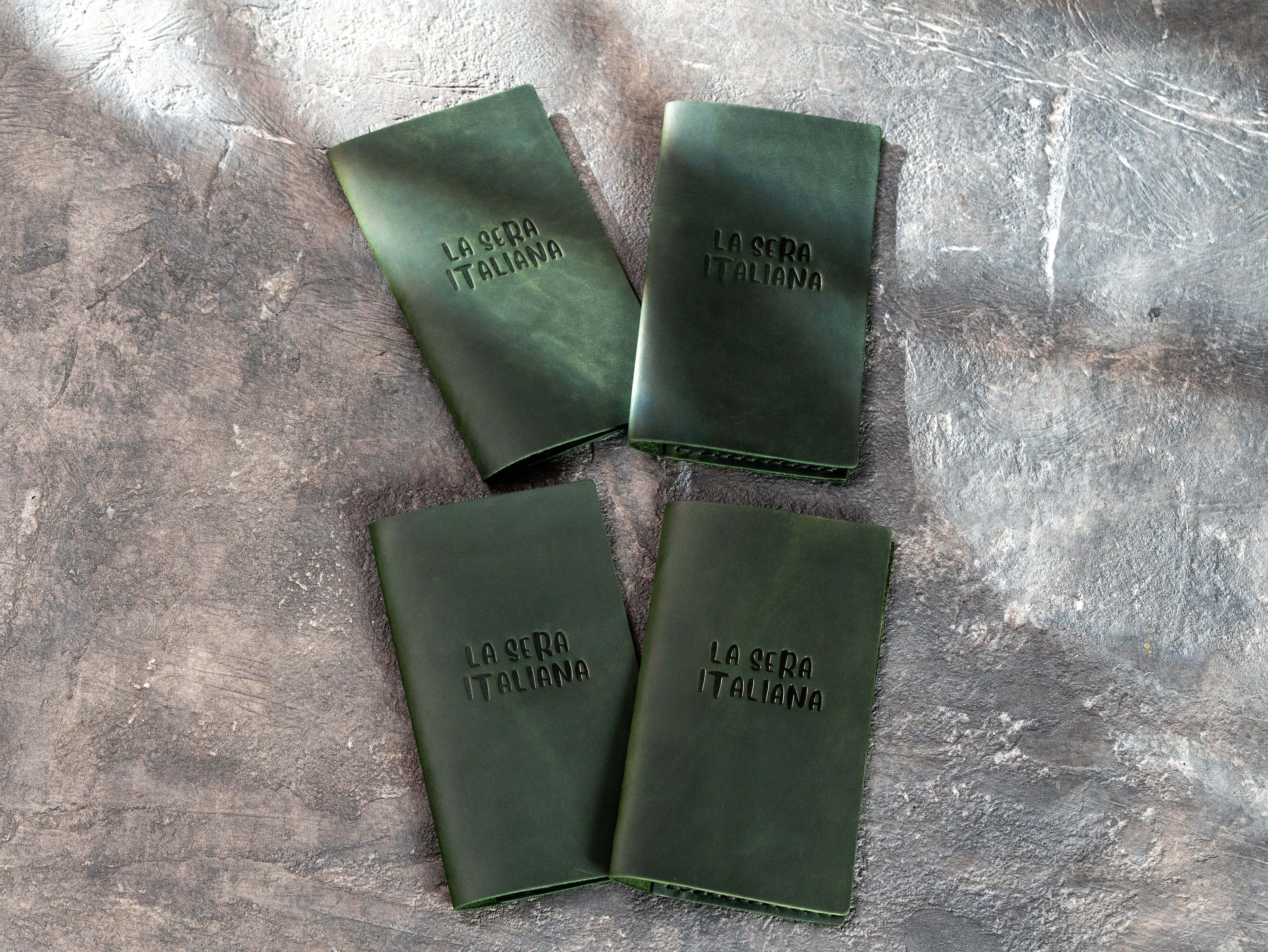 Four custom green leather check presenters made for an Italian restaurant