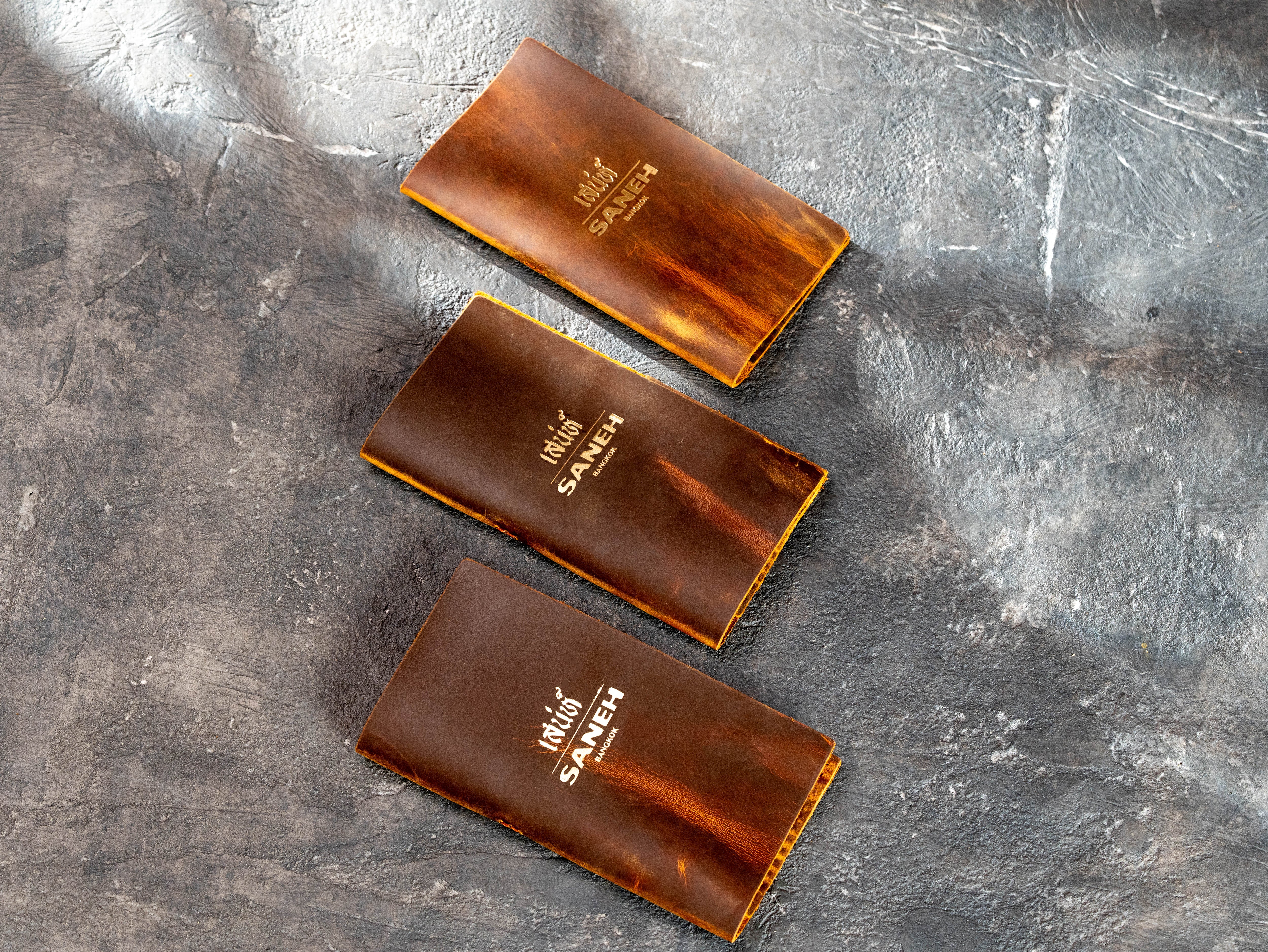 Custom brown chestnut leather check presenters with gold logo and natural Crazy Horse texture
