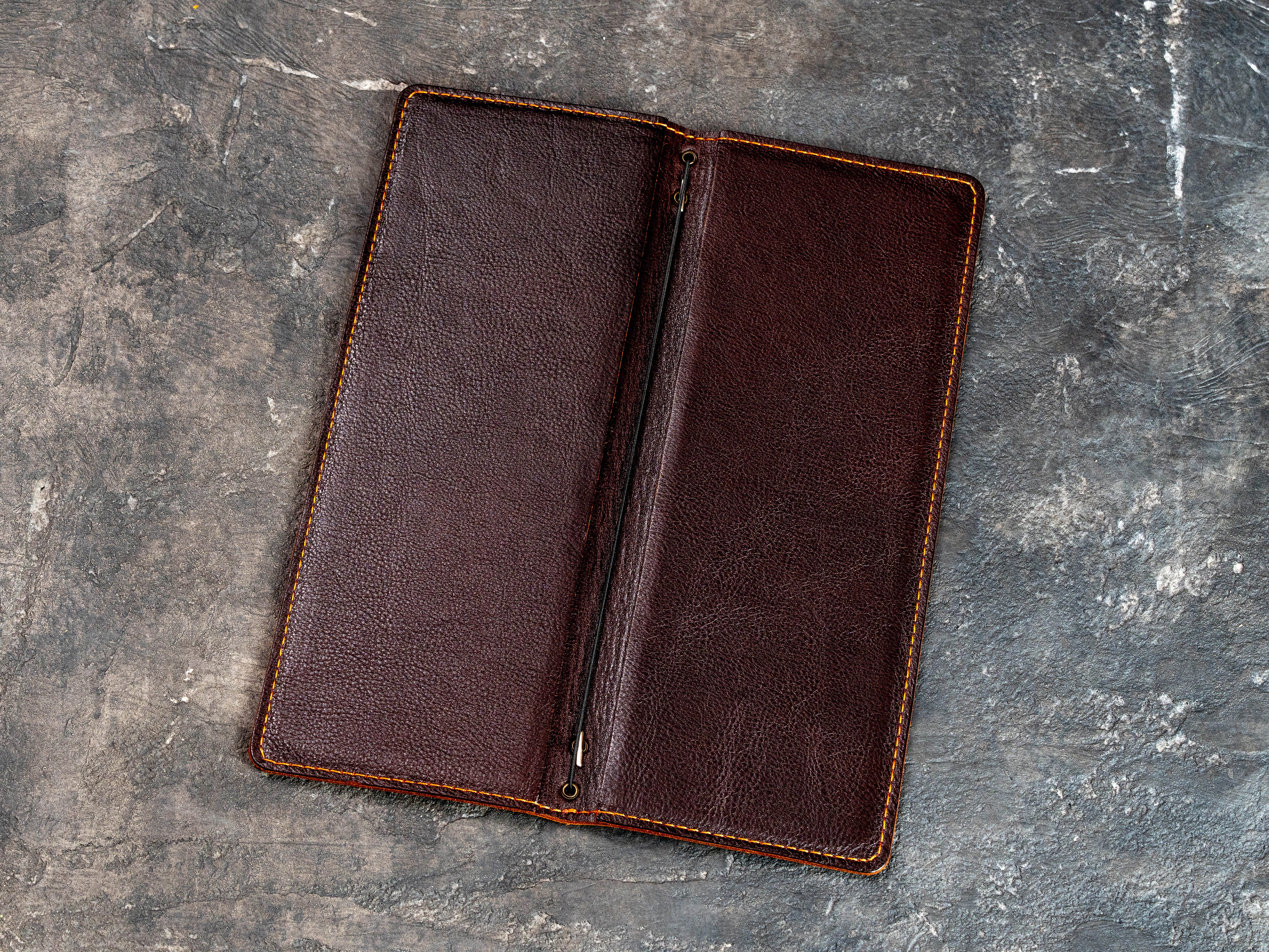 Open dark brown leather menu cover showing double-layer construction and elastic cord binding