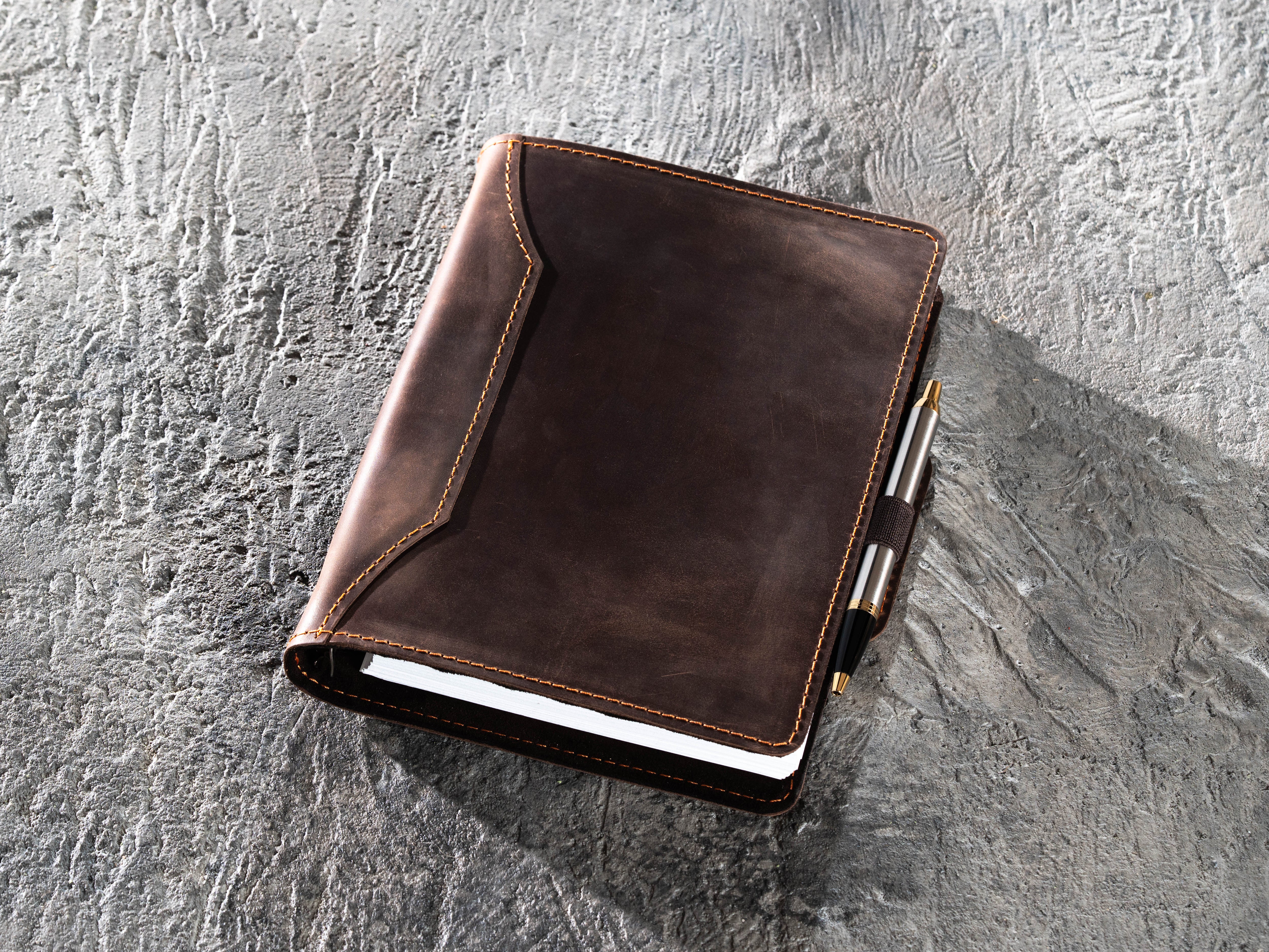 Dark brown leather A5 binder notebook with pen secured in the elastic side holder