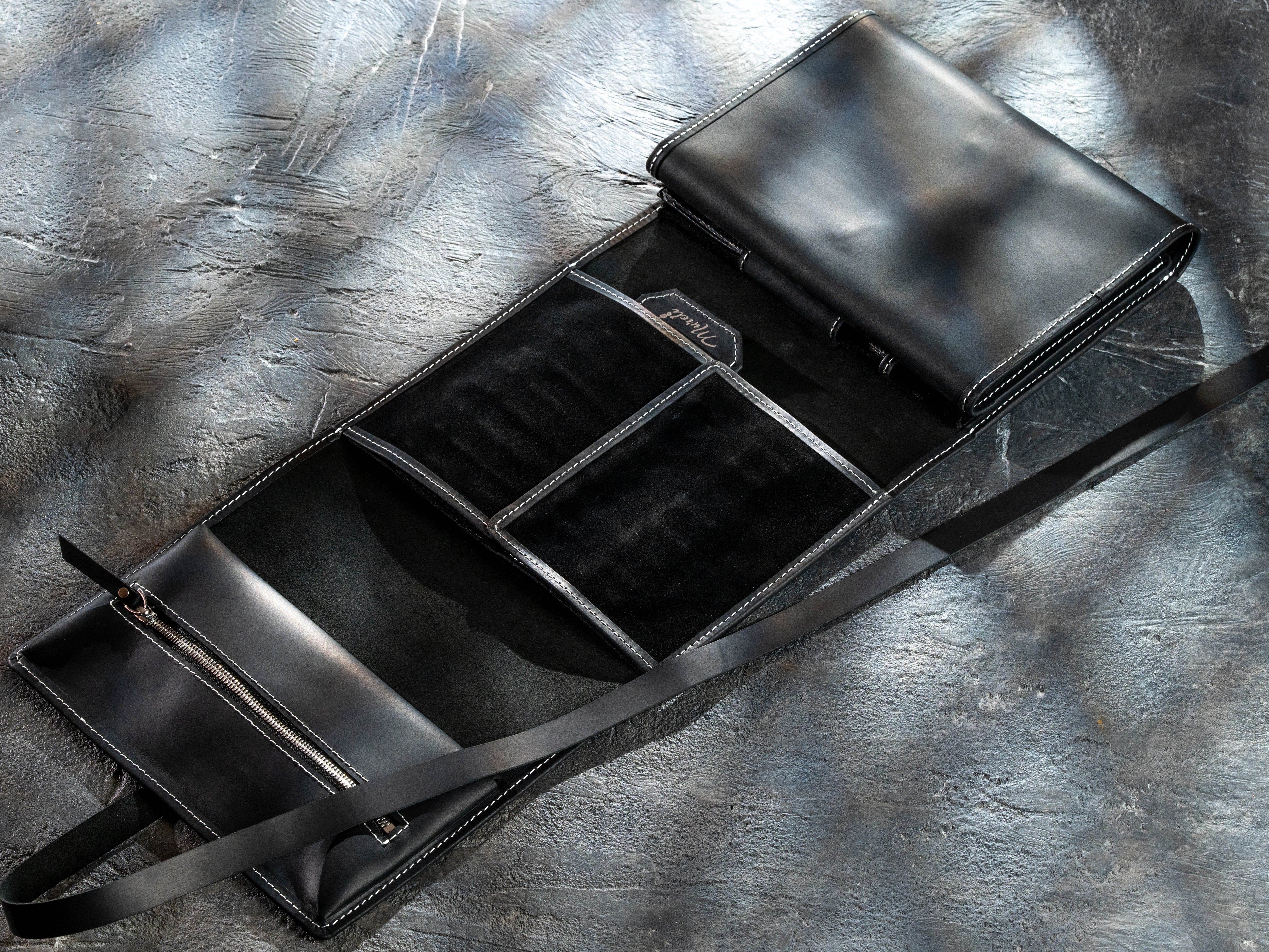 Open black leather artist organizer showing multiple storage compartments and removable sections