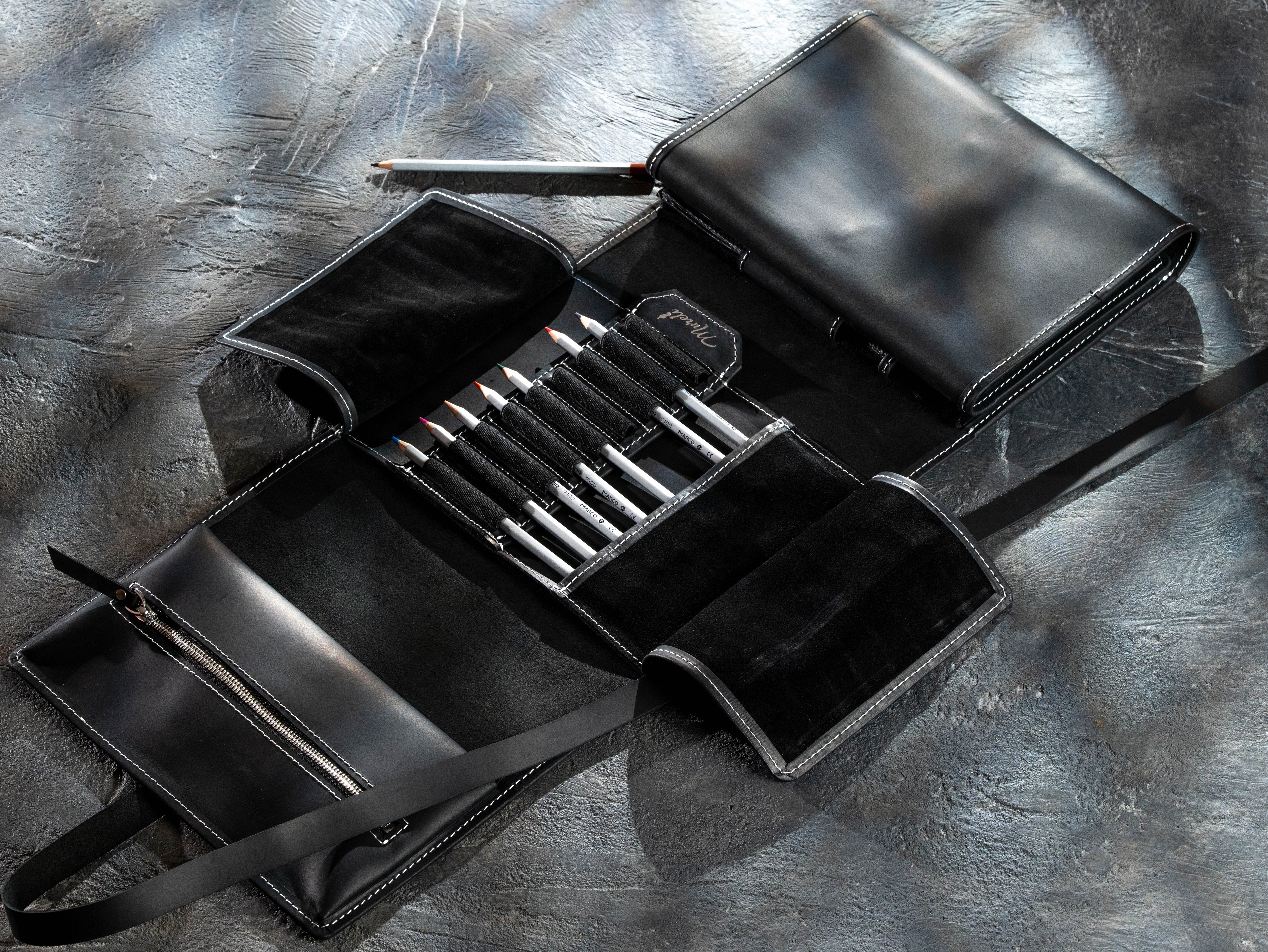 Black leather artist organizer filled with colored pencils and drawing tools