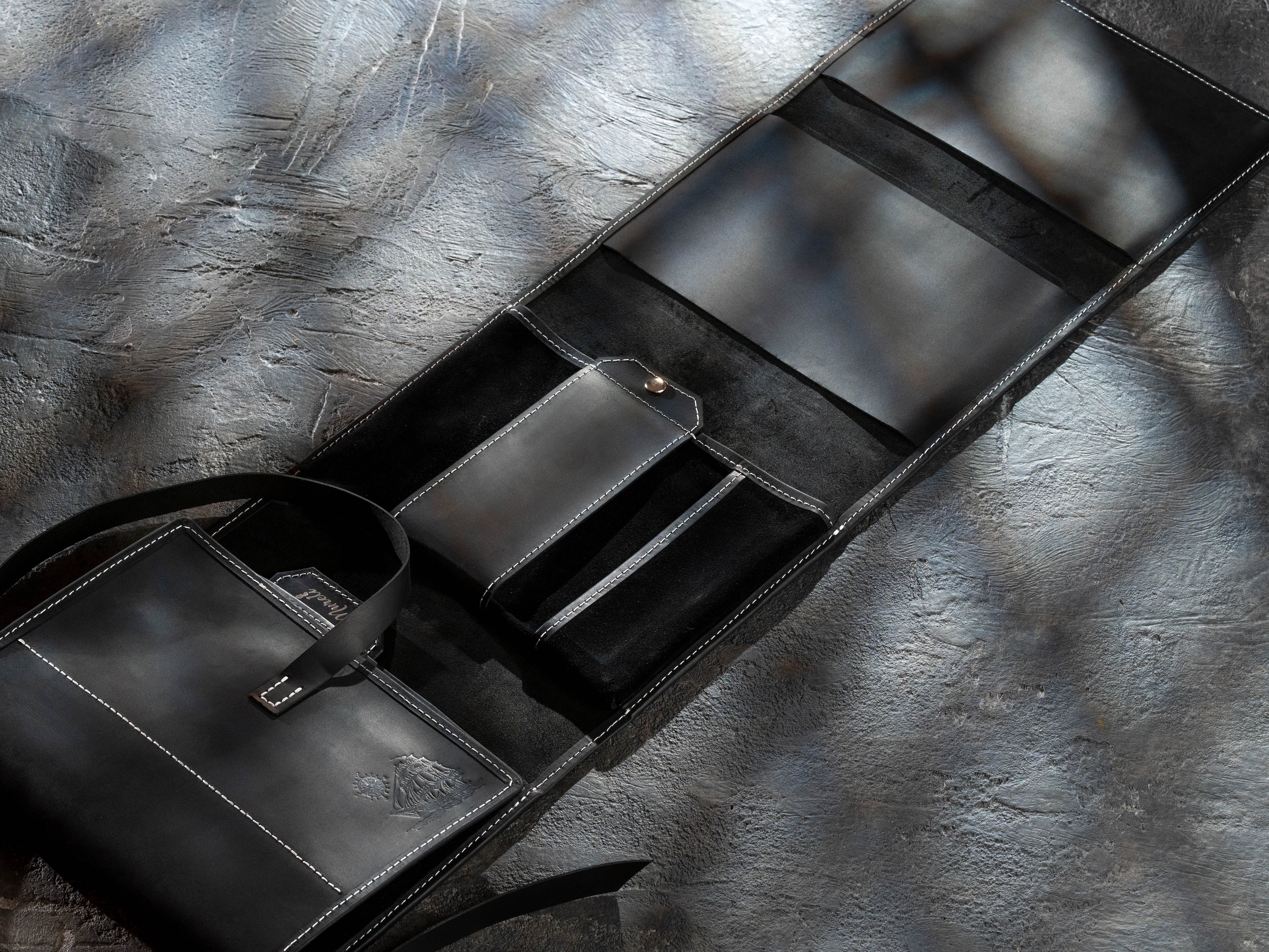 Empty black leather artist organizer displaying interior pockets, straps and modular storage sections