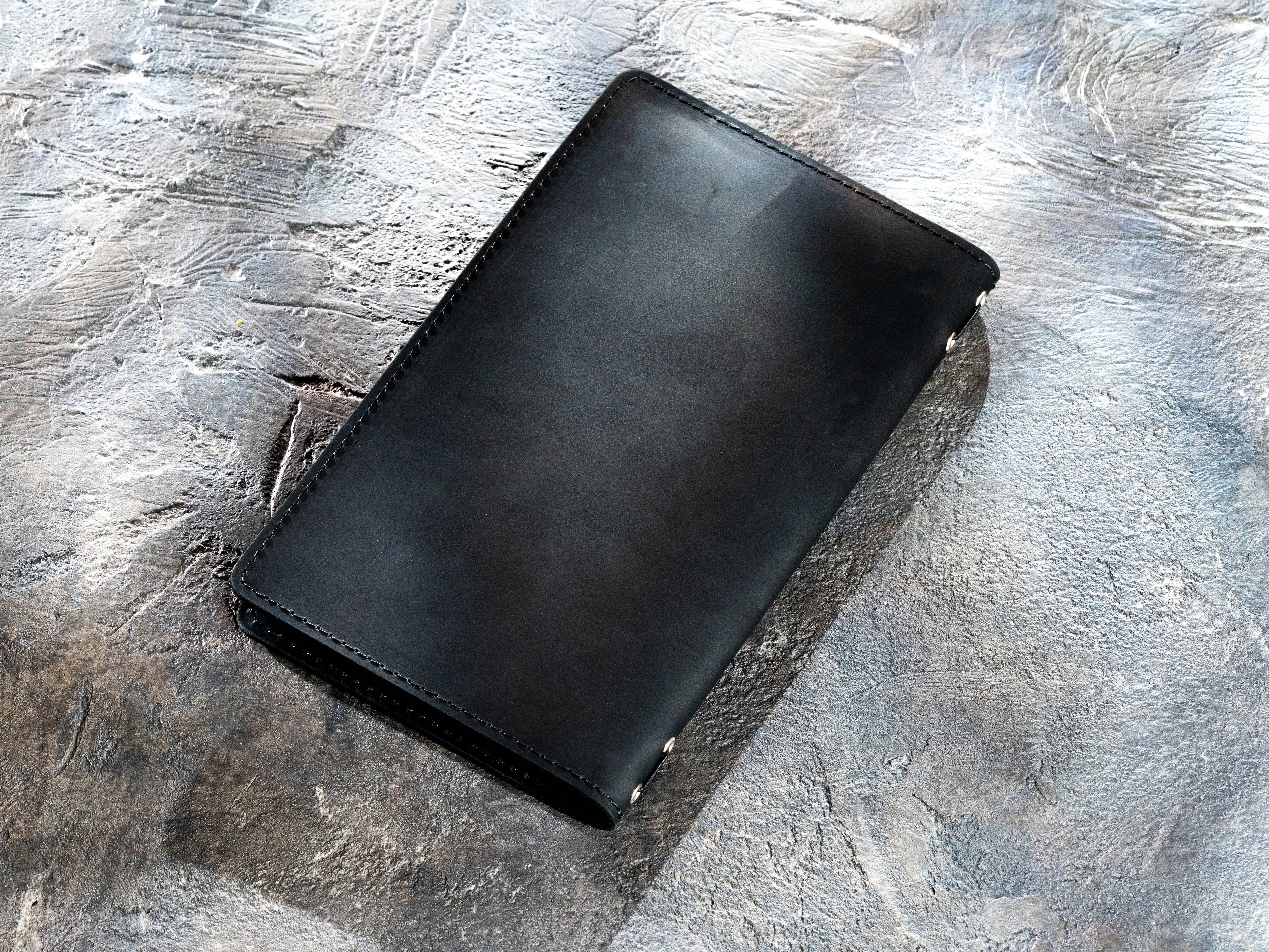 Back view of black leather menu cover with stitched edges and smooth finish