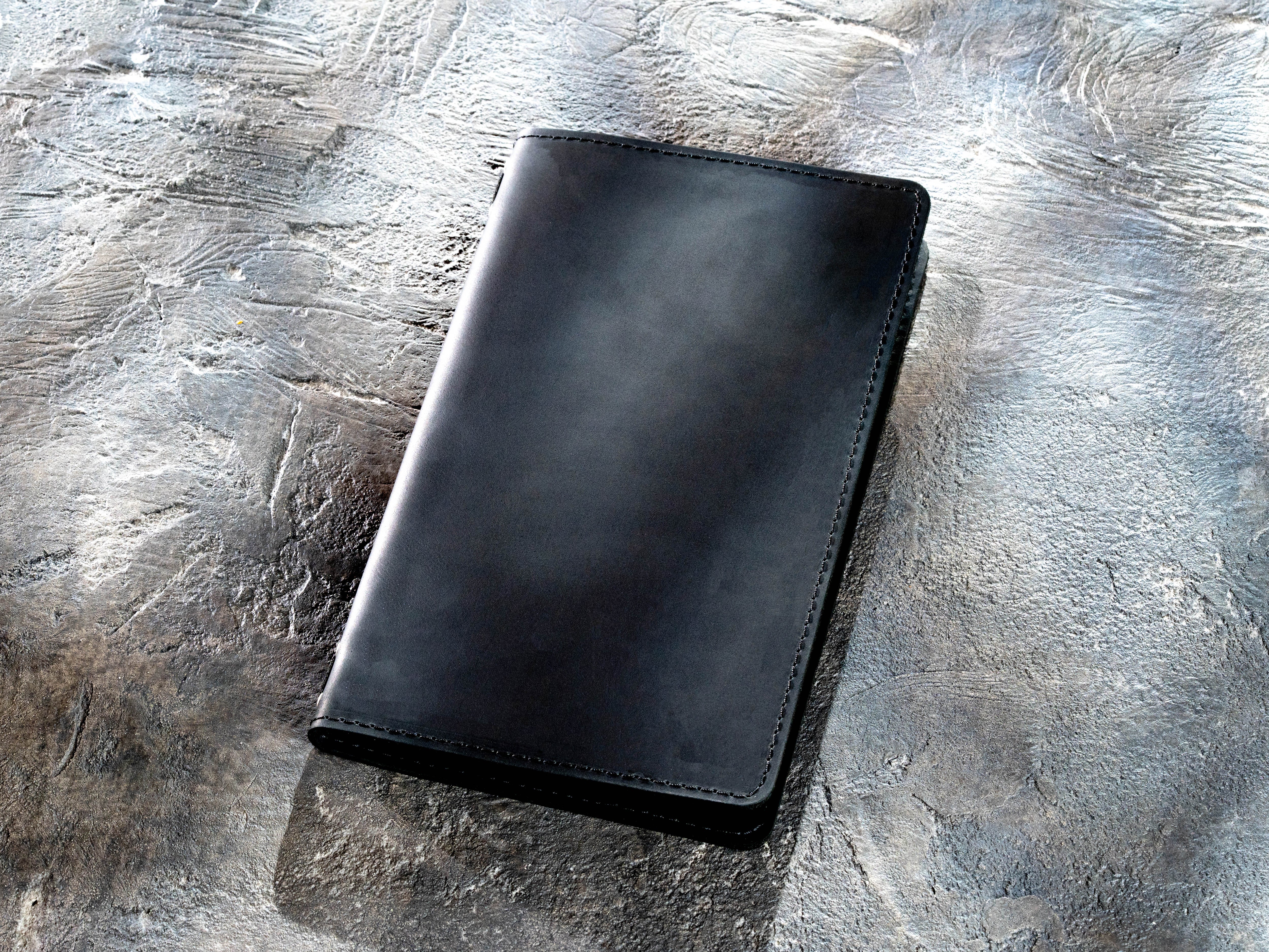 Closed black leather menu cover with custom embossed logo and elastic cord binding