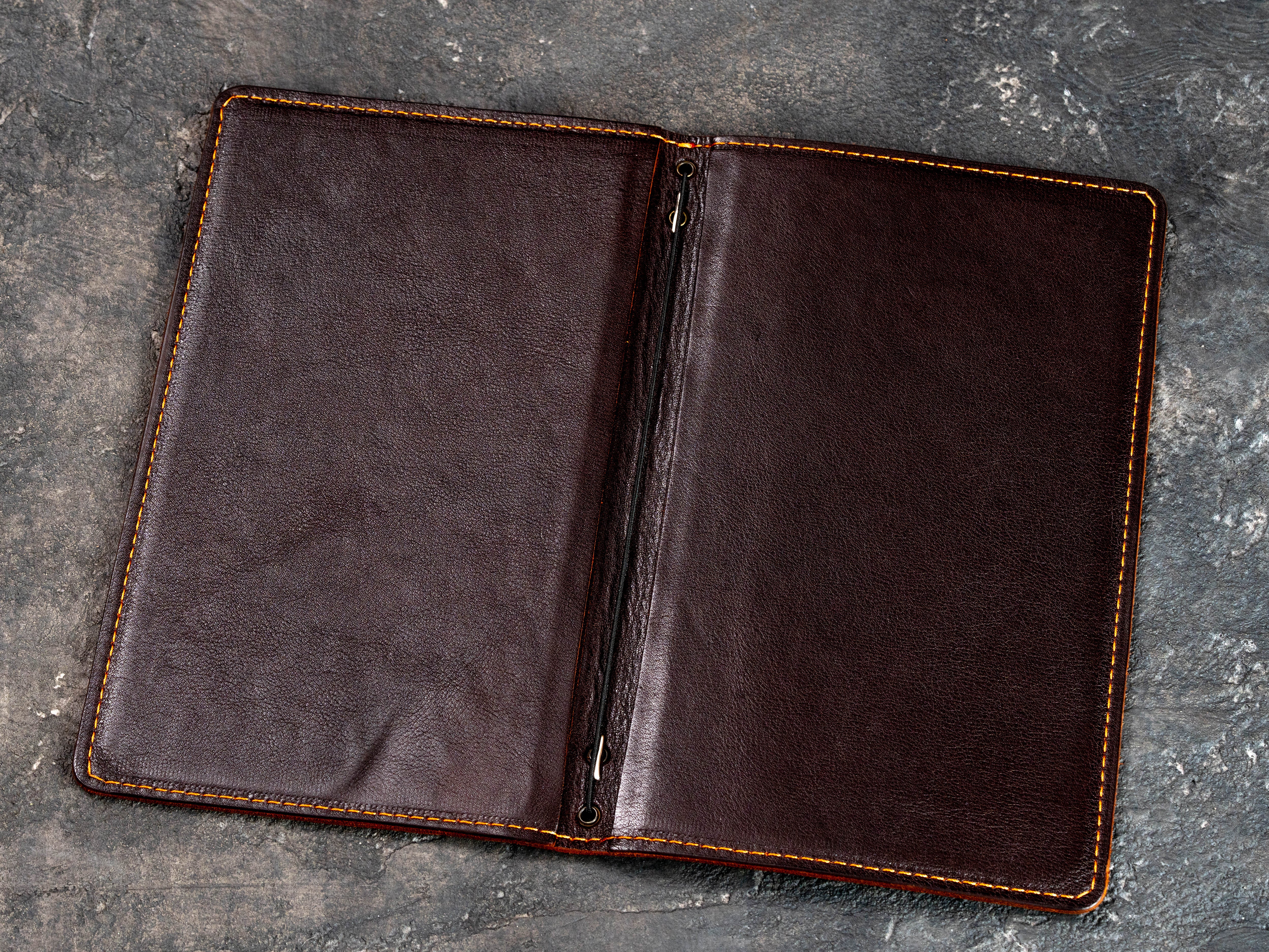 Open cognac leather menu cover showing the double-layer interior and elastic cord binding