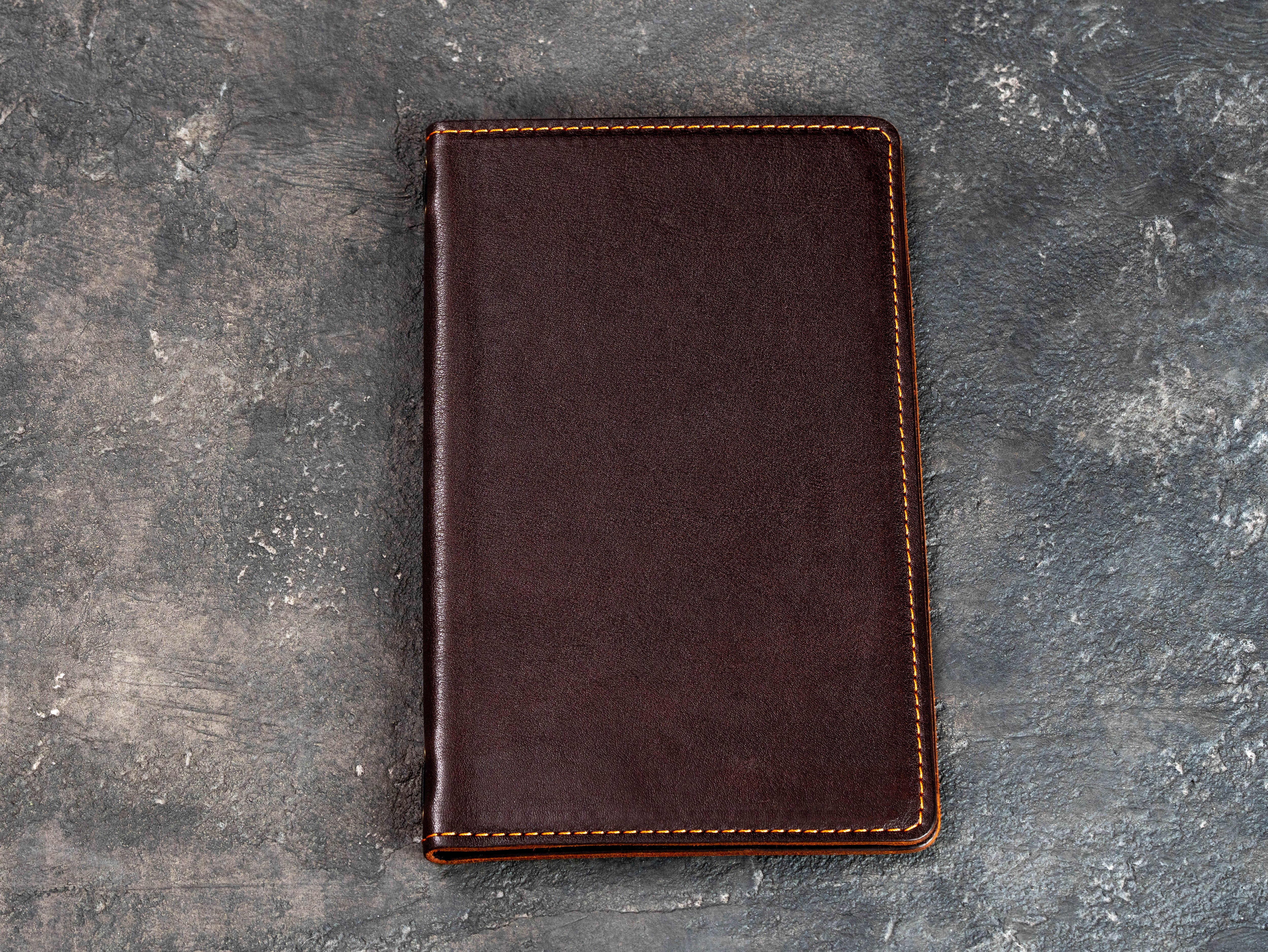 Closed cognac leather restaurant menu cover shown from a slight angle on a dark textured background