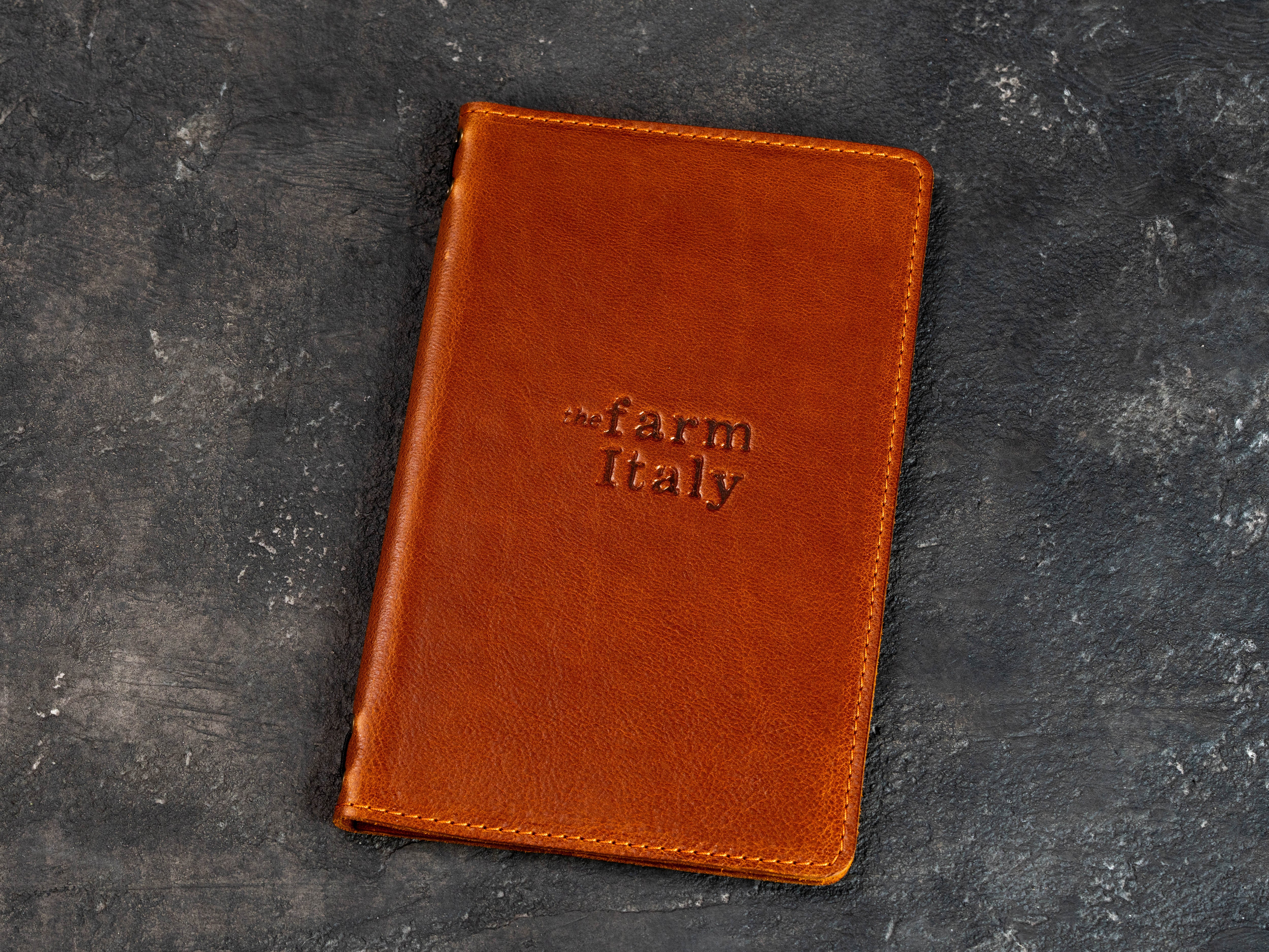 Closed camel leather restaurant menu cover with a custom embossed logo on the front