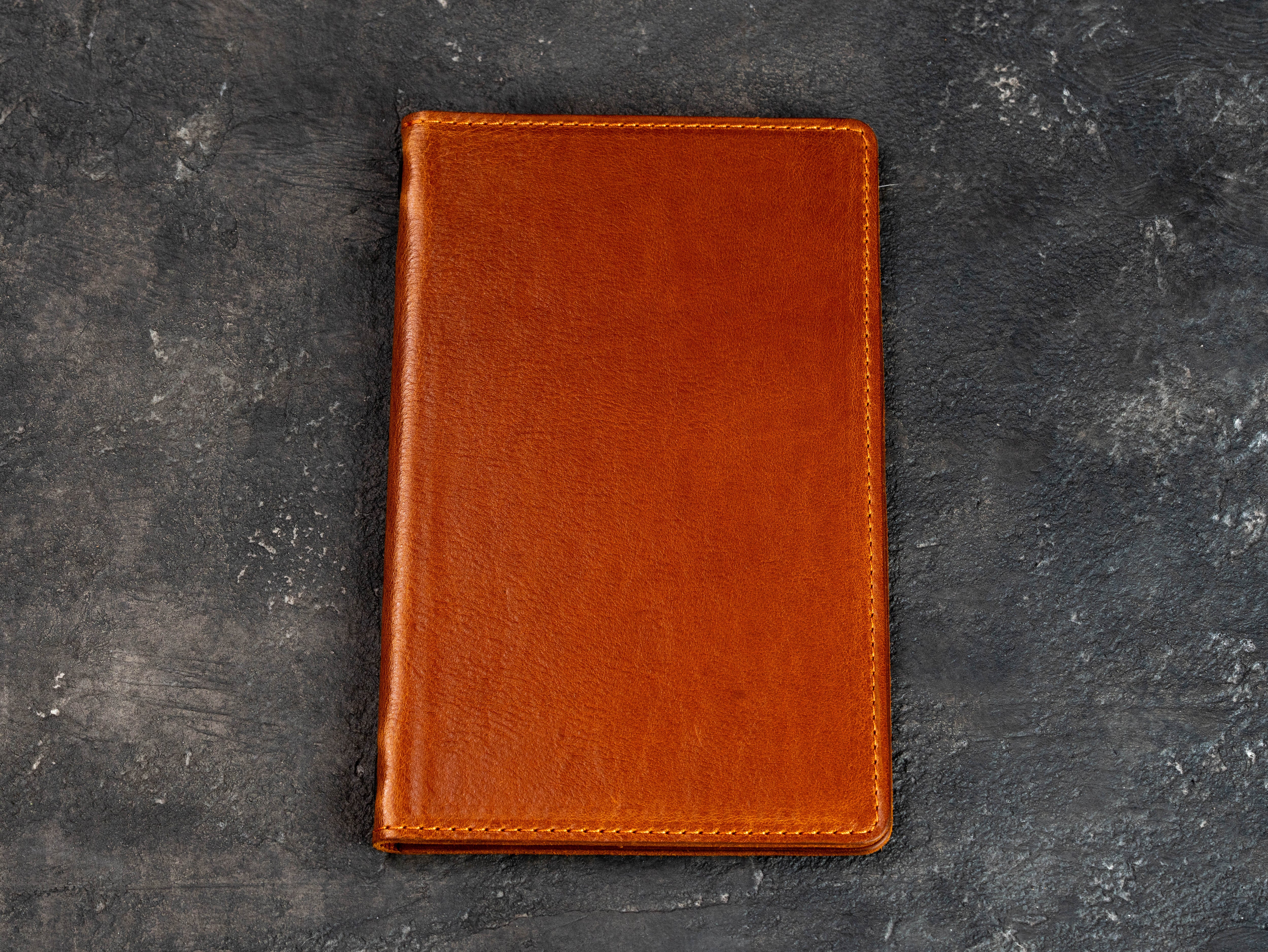 Closed camel leather restaurant menu cover shown from a slight angle on a dark textured background