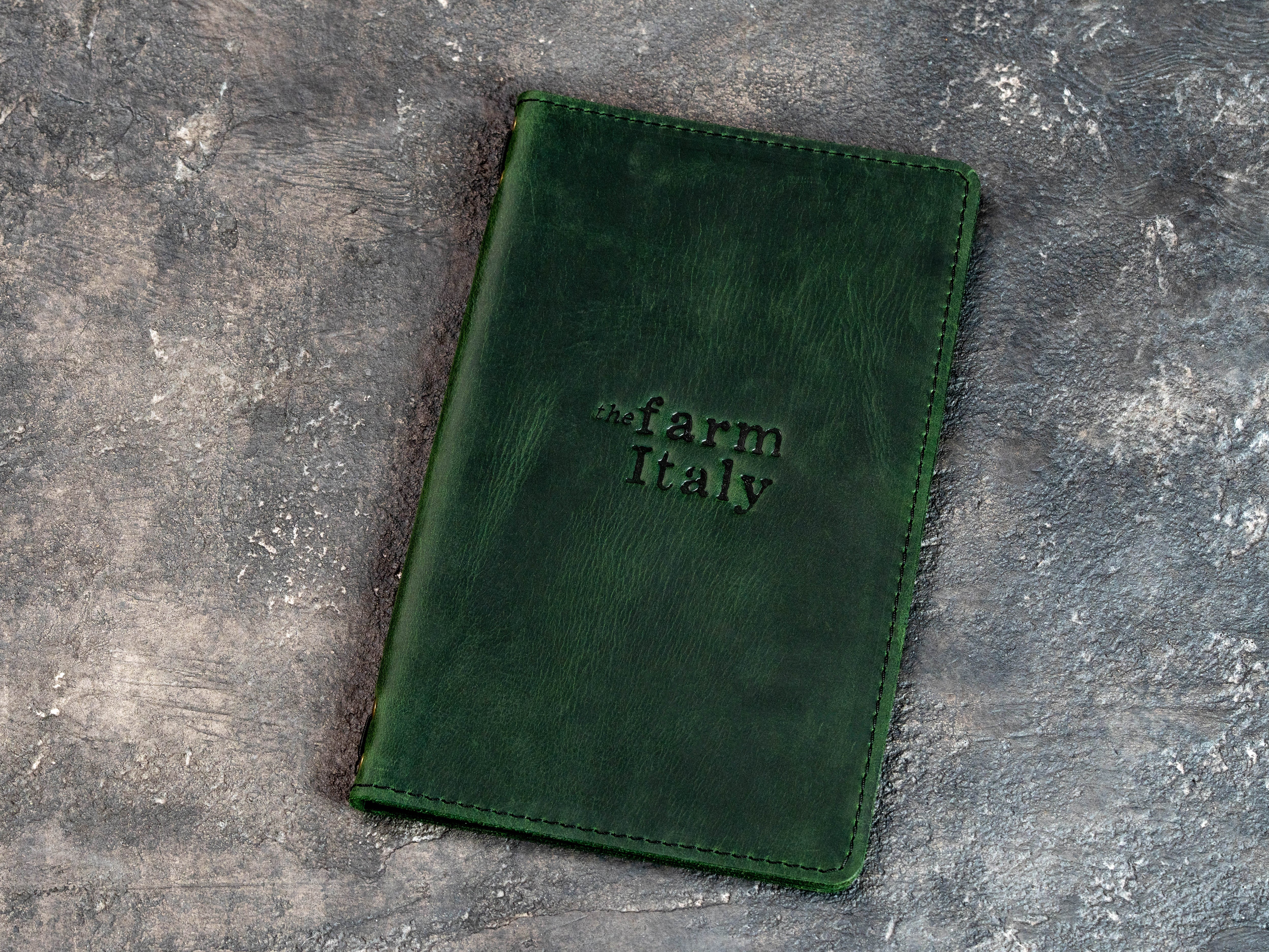 Closed green double-layer leather restaurant menu cover with stitched edges