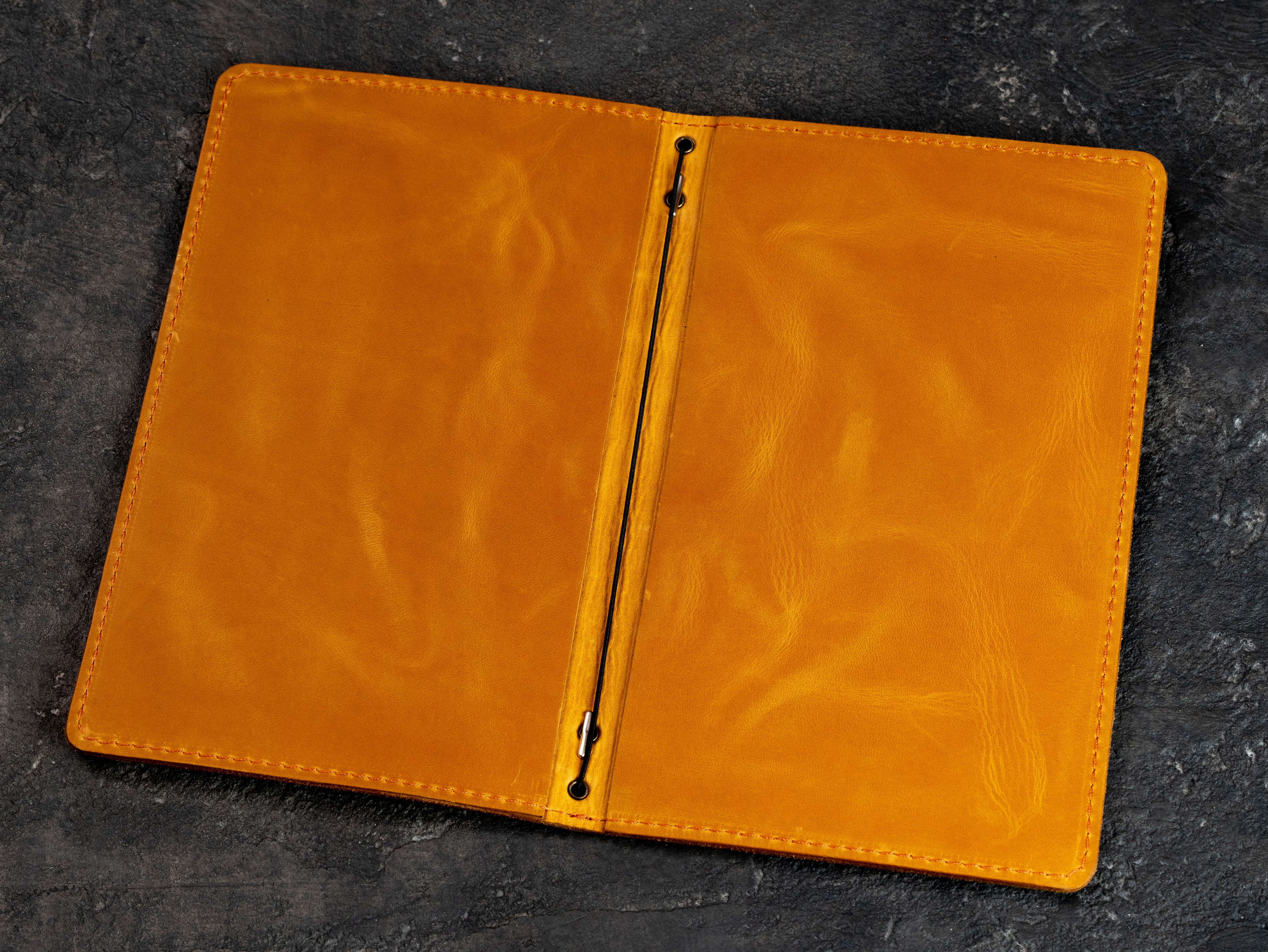 Open golden yellow leather menu cover showing double-layer construction and central elastic binding