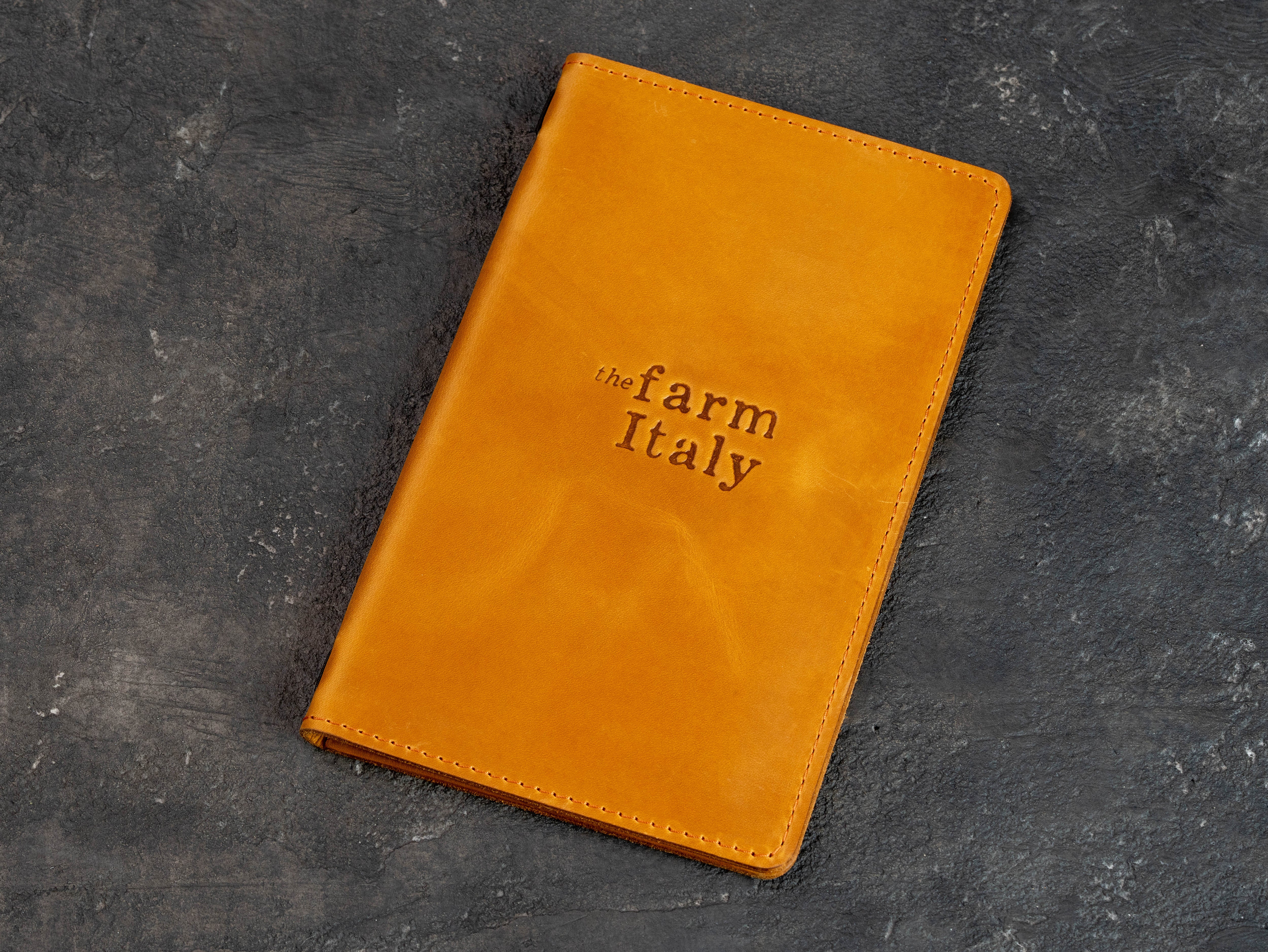 Closed golden yellow leather restaurant menu cover with custom embossed logo